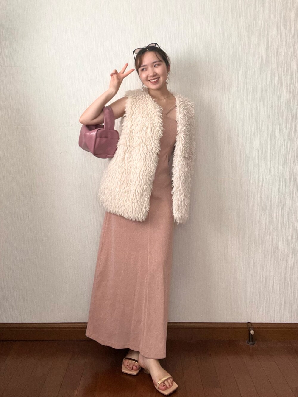 ホワイト系のベスト、オレンジ系のワンピース、ピンク系のボストンバッグを着用したレディースの秋コーディネートの4枚目の写真