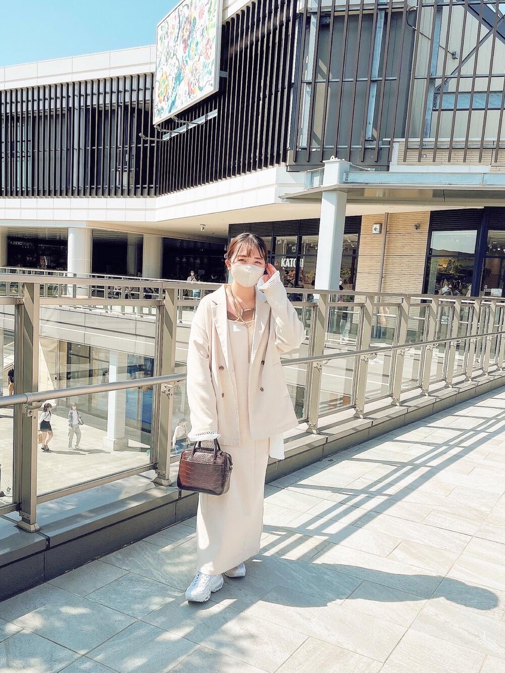 ホワイト系のワンピース、ホワイト系のテーラードジャケット、ブラウン系のショルダーバッグを着用したレディースの春コーディネートの2枚目の写真