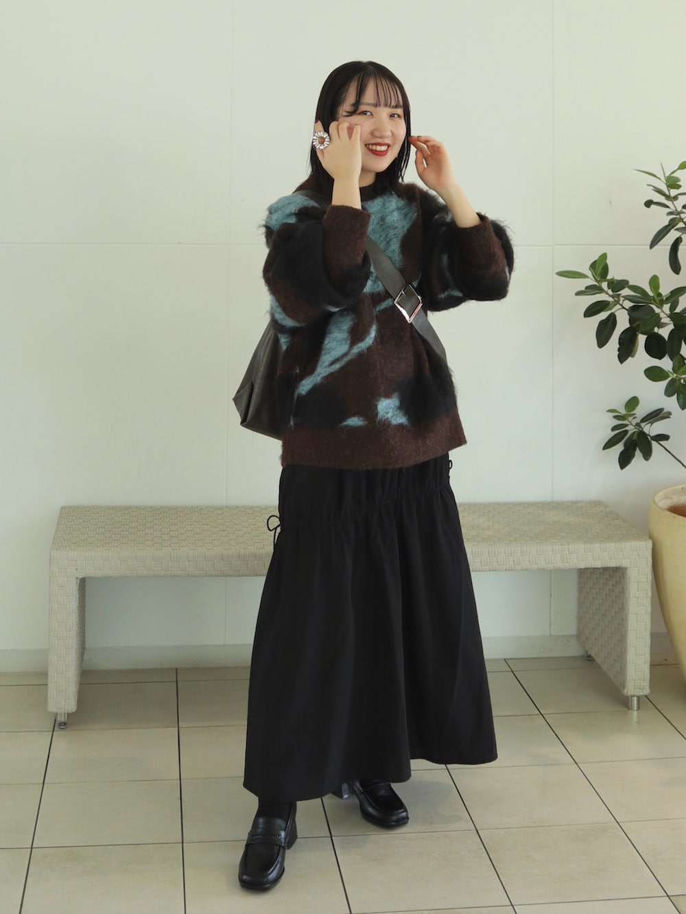 ブラウン系のニット/セーター、ブラック系のスカート、ブラウン系のショルダーバッグを着用したレディースの秋コーディネートの2枚目の写真
