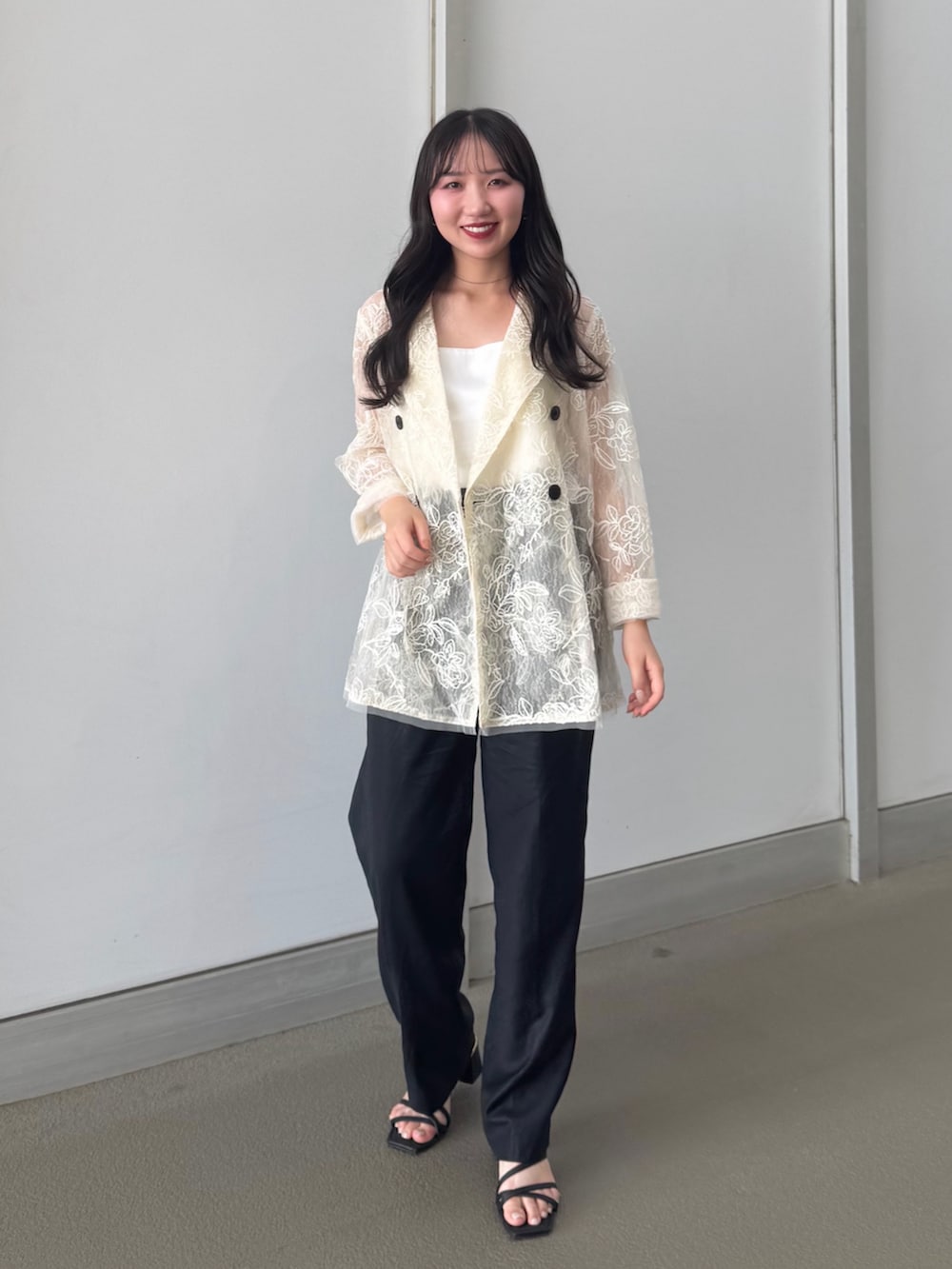 ホワイト系のテーラードジャケット、ホワイト系のキャミソール、ブラック系のパンツを着用したレディースの夏コーディネートの3枚目の写真