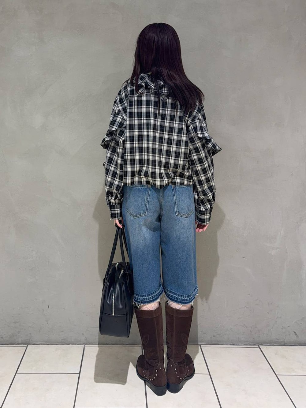 ブラック系のボストンバッグ、ブラウン系のブーツ、ブラック系のシャツ/ブラウスを着用したレディースの春コーディネートの3枚目の写真