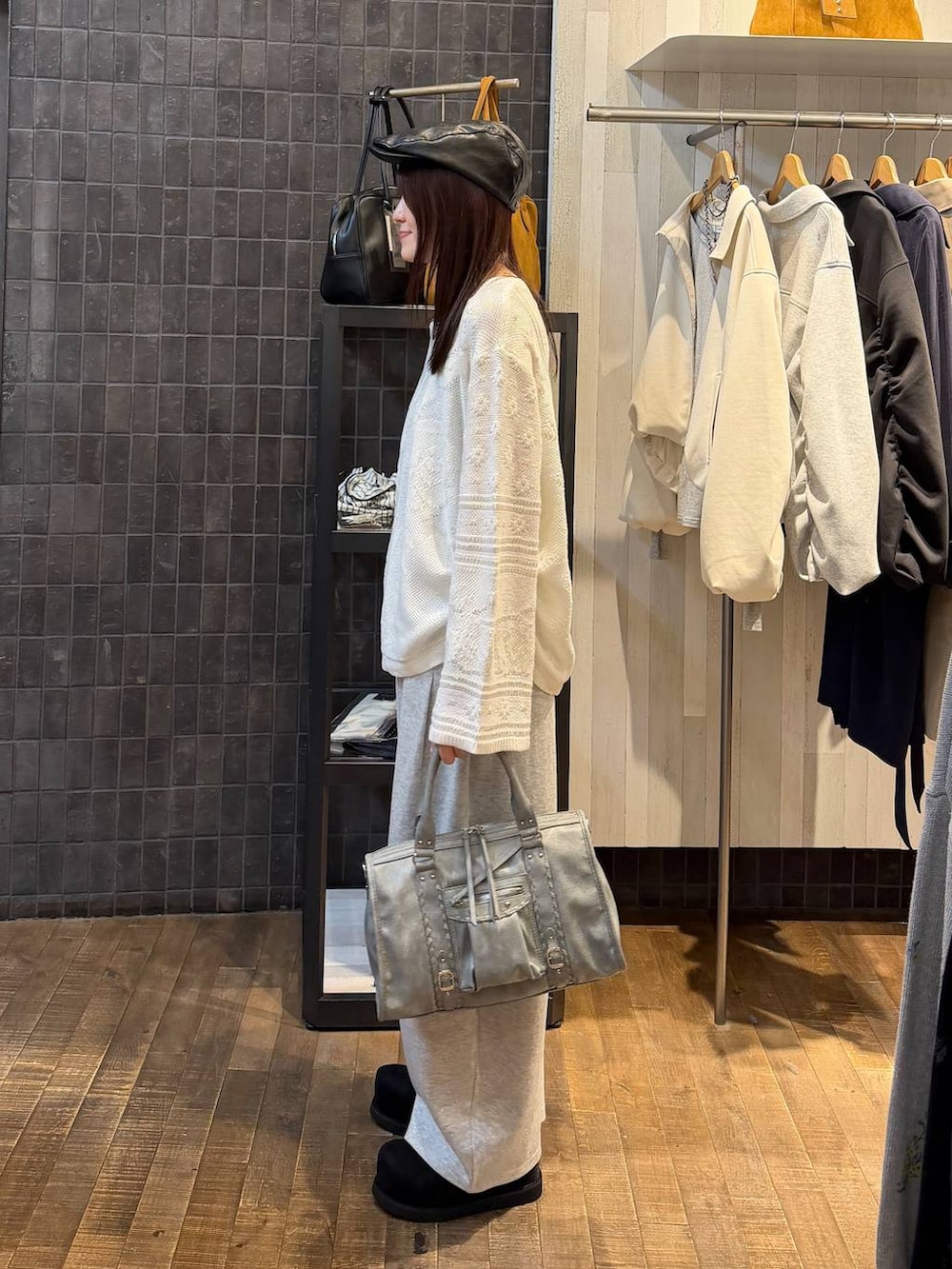 ブラック系のモカシン/デッキシューズ、ブルー系のボストンバッグ、ホワイト系のニット/セーターを着用したレディースの春コーディネートの2枚目の写真