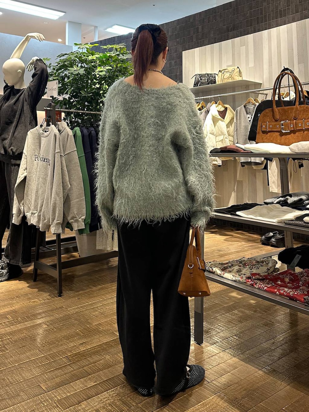 ブラック系のパンプス、ブラウン系のボストンバッグ、ブラック系のスウェットパンツを着用したレディースの冬コーディネートの3枚目の写真