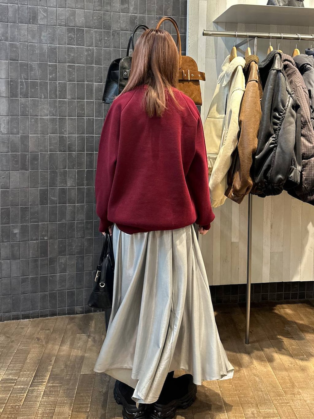 ブラック系のブーツ、ブラック系のボストンバッグ、シルバー系のスカートを着用したレディースの秋コーディネートの3枚目の写真