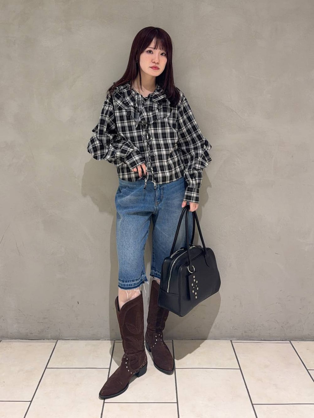 ブラック系のボストンバッグ、ブラウン系のブーツ、ブラック系のシャツ/ブラウスを着用したレディースの春コーディネートの4枚目の写真