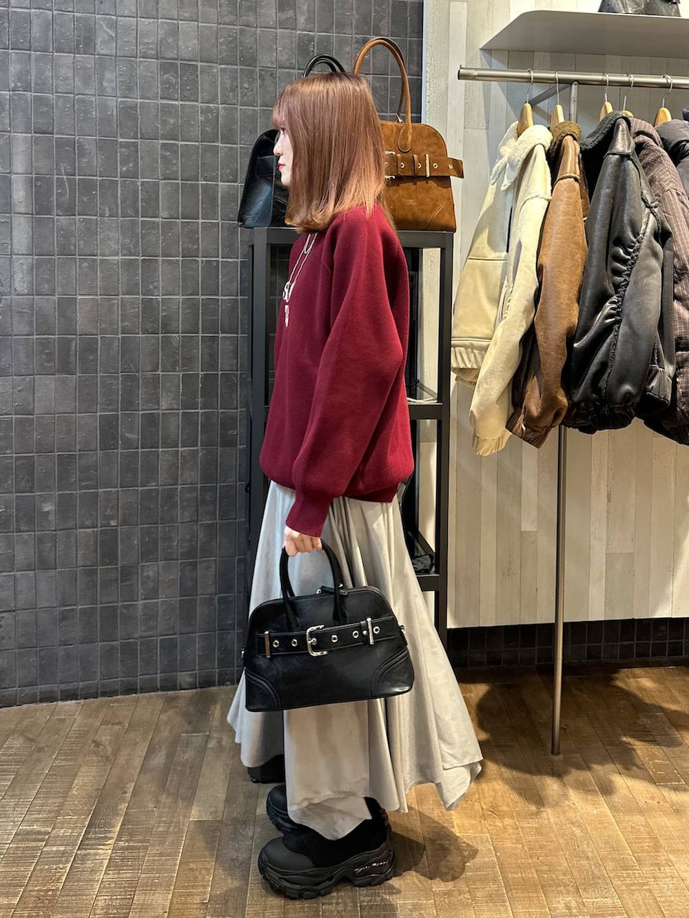 ブラック系のブーツ、ブラック系のボストンバッグ、シルバー系のスカートを着用したレディースの秋コーディネートの2枚目の写真