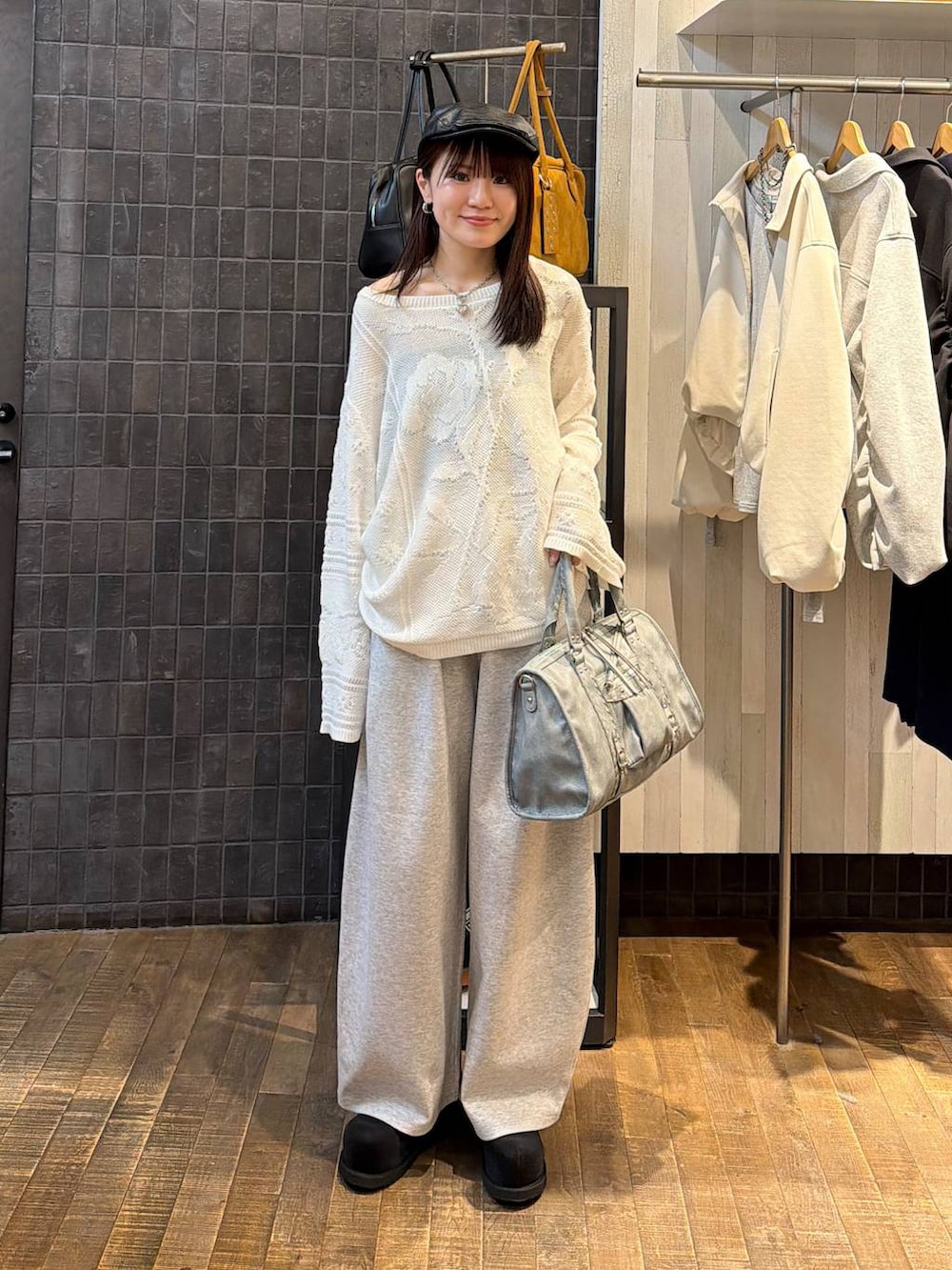 ブラック系のモカシン/デッキシューズ、ブルー系のボストンバッグ、ホワイト系のニット/セーターを着用したレディースの春コーディネートの4枚目の写真