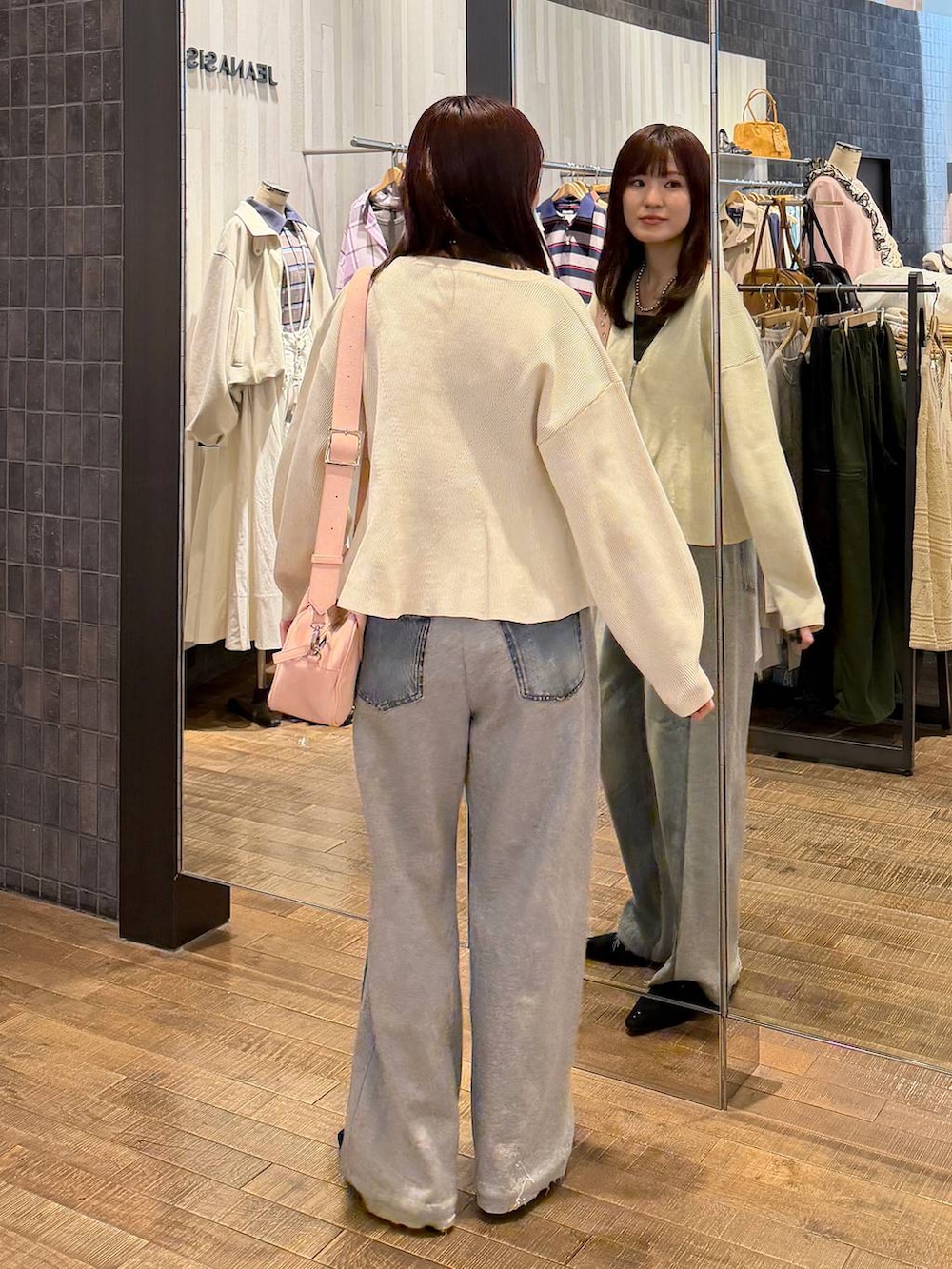 ピンク系のボストンバッグ、ブラック系のパンプス、ブルー系のデニムパンツを着用したレディースの冬コーディネートの3枚目の写真