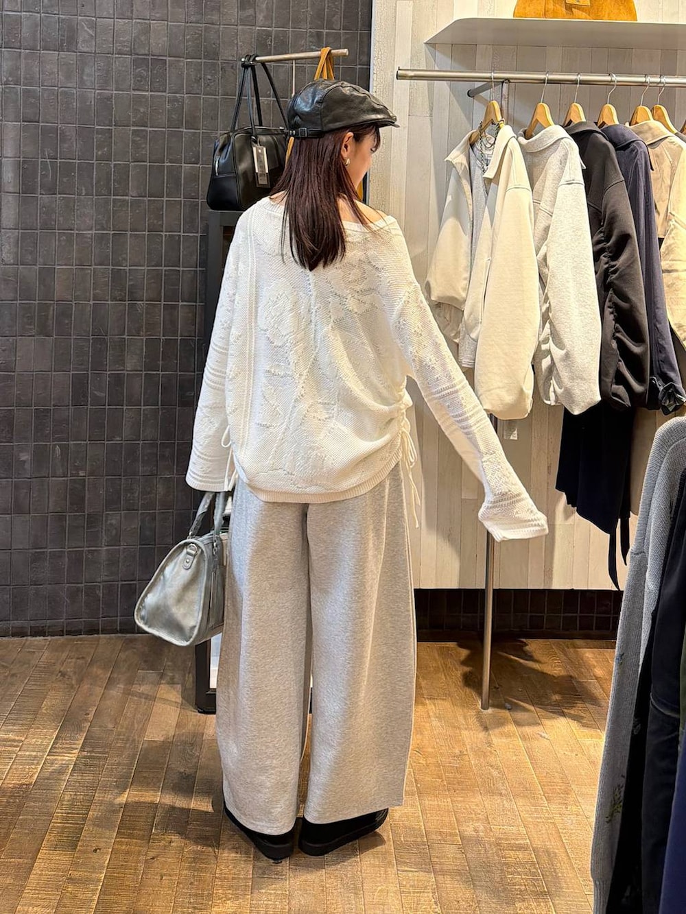 ブラック系のモカシン/デッキシューズ、ブルー系のボストンバッグ、ホワイト系のニット/セーターを着用したレディースの春コーディネートの3枚目の写真