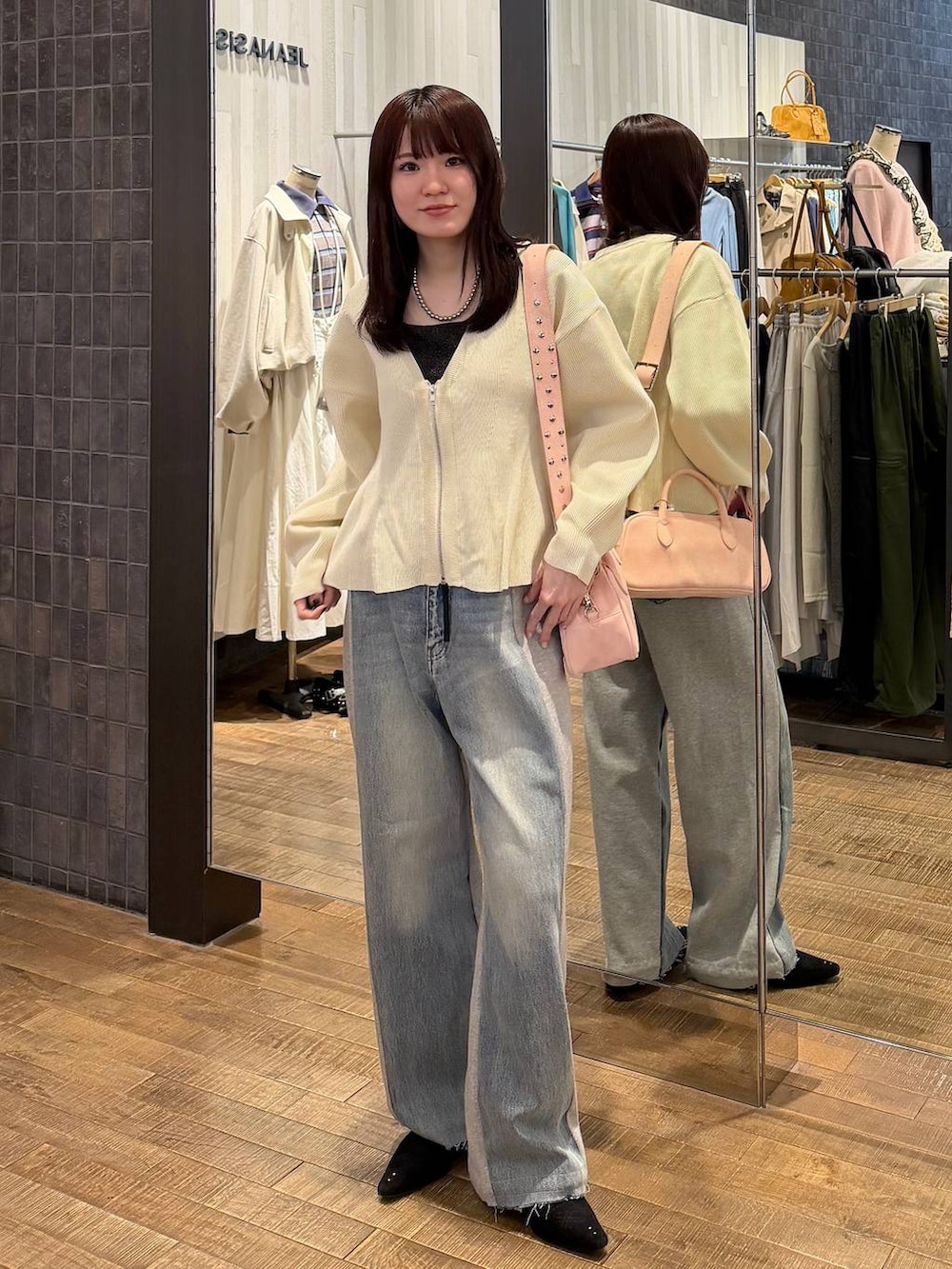 ピンク系のボストンバッグ、ブラック系のパンプス、ブルー系のデニムパンツを着用したレディースの冬コーディネートの4枚目の写真