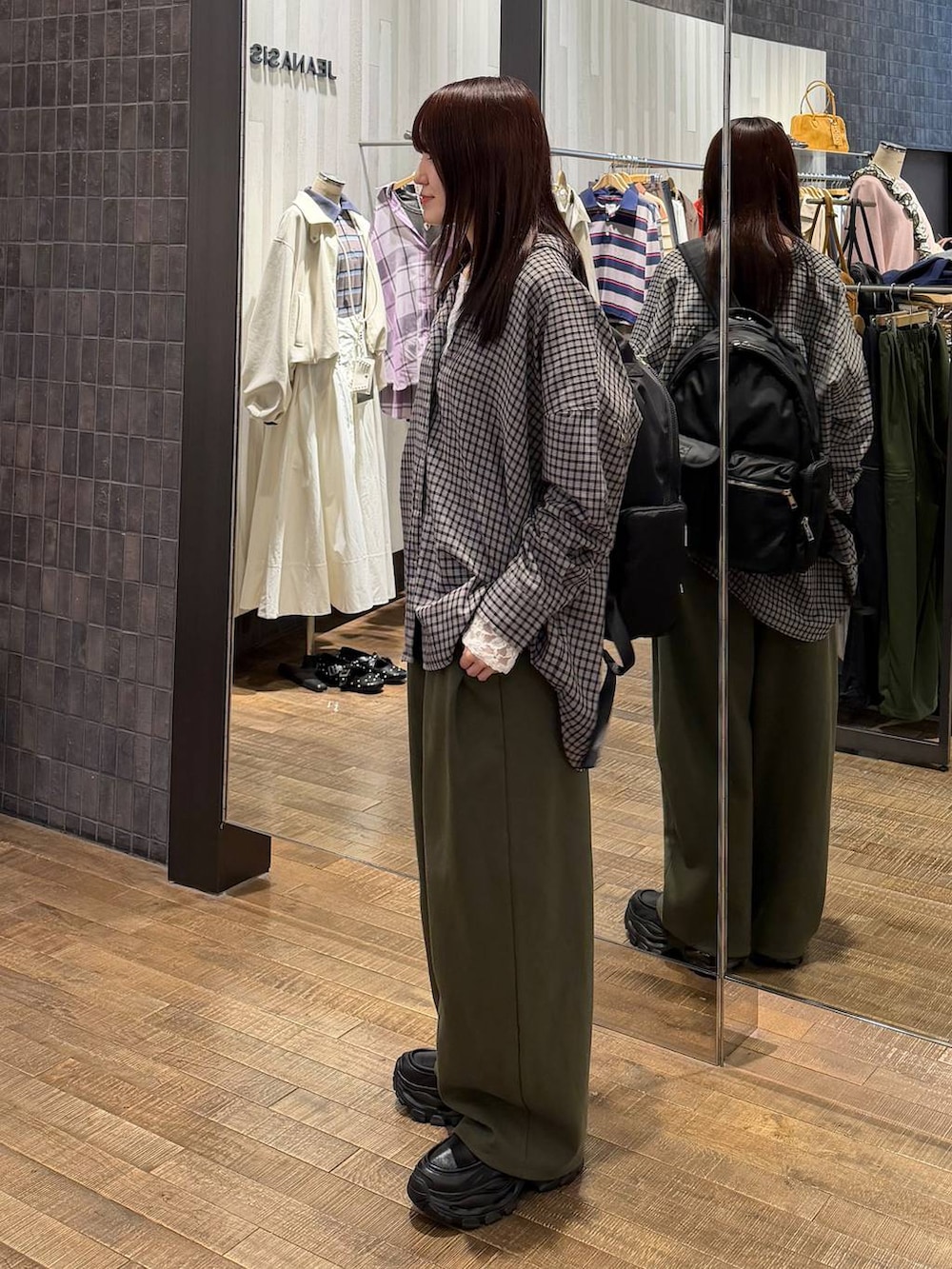 ブラック系のシャツ/ブラウス、ブラック系のローファー、グリーン系のスウェットパンツを着用したレディースの冬コーディネートの2枚目の写真