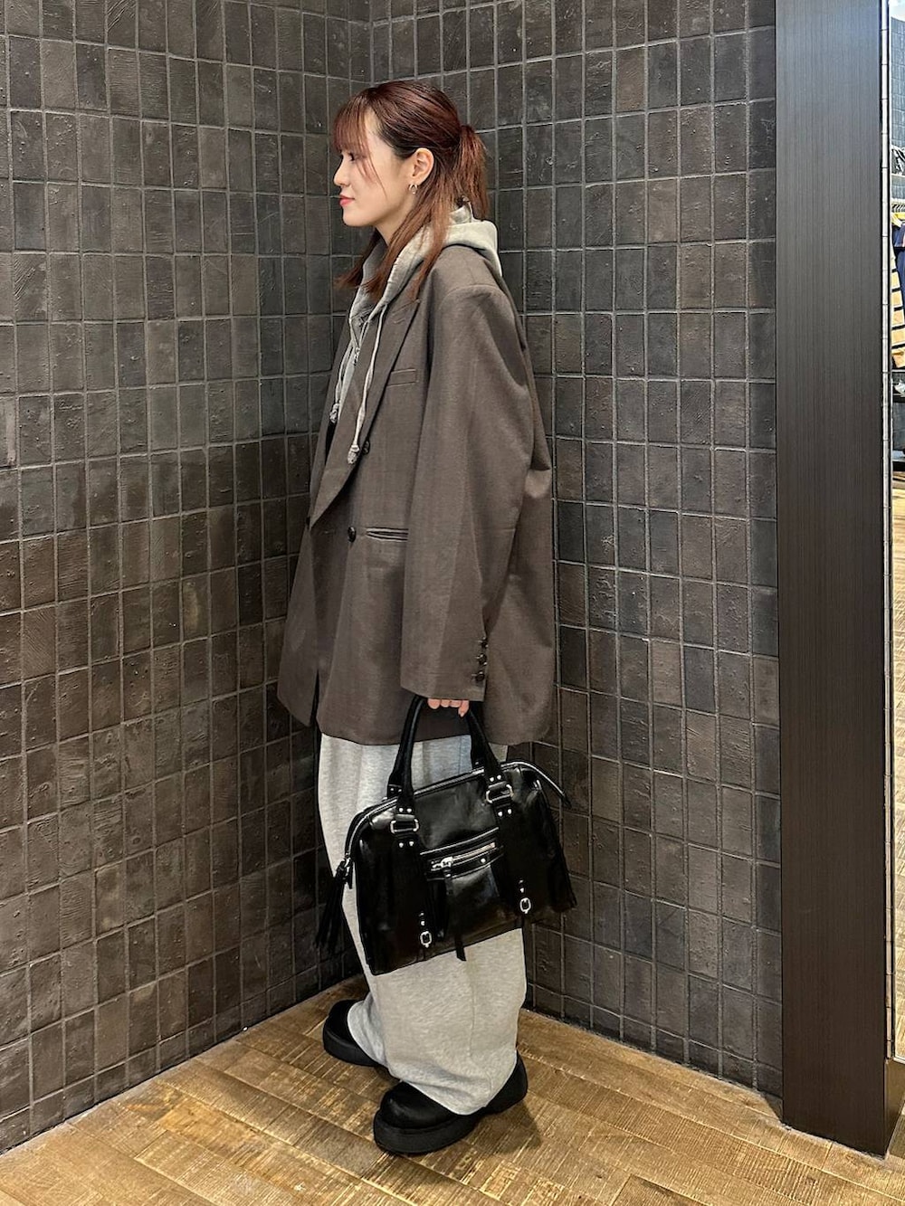 ブラック系のサンダル、グレー系のパーカー、ブラック系のボストンバッグを着用したレディースの秋コーディネートの2枚目の写真