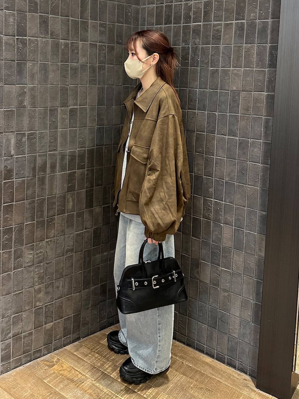 ブルー系のデニムパンツ、ブラウン系のブルゾン、ブラック系のローファーを着用したレディースの秋コーディネートの2枚目の写真