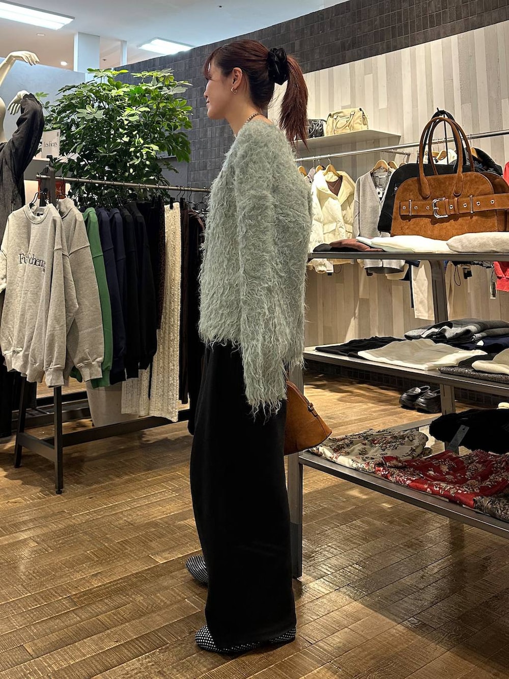 ブラック系のパンプス、ブラウン系のボストンバッグ、ブラック系のスウェットパンツを着用したレディースの冬コーディネートの2枚目の写真