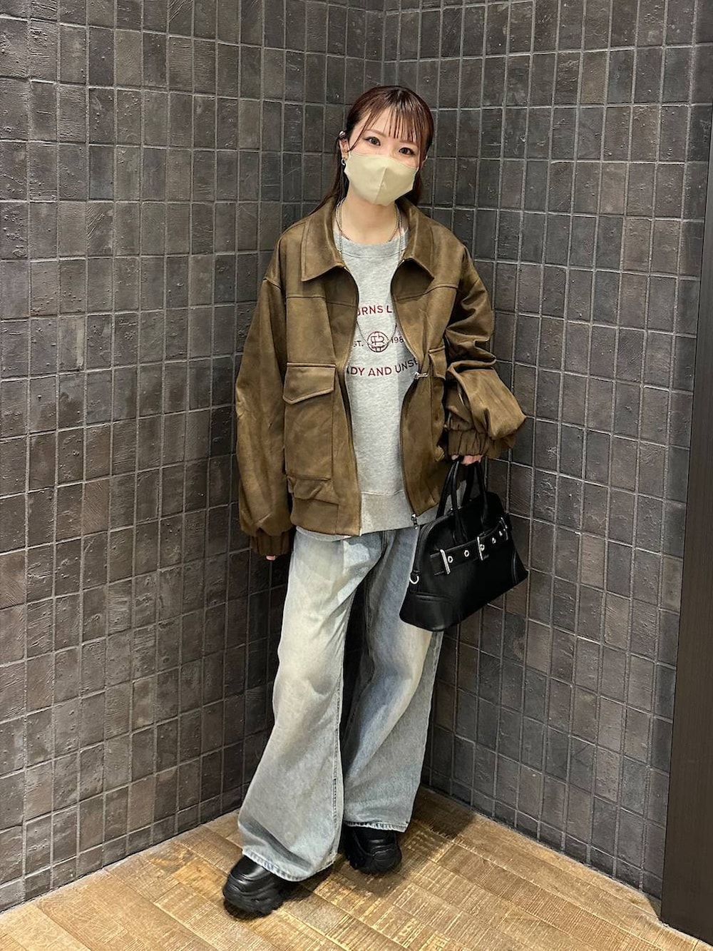 ブルー系のデニムパンツ、ブラウン系のブルゾン、ブラック系のローファーを着用したレディースの秋コーディネートの4枚目の写真