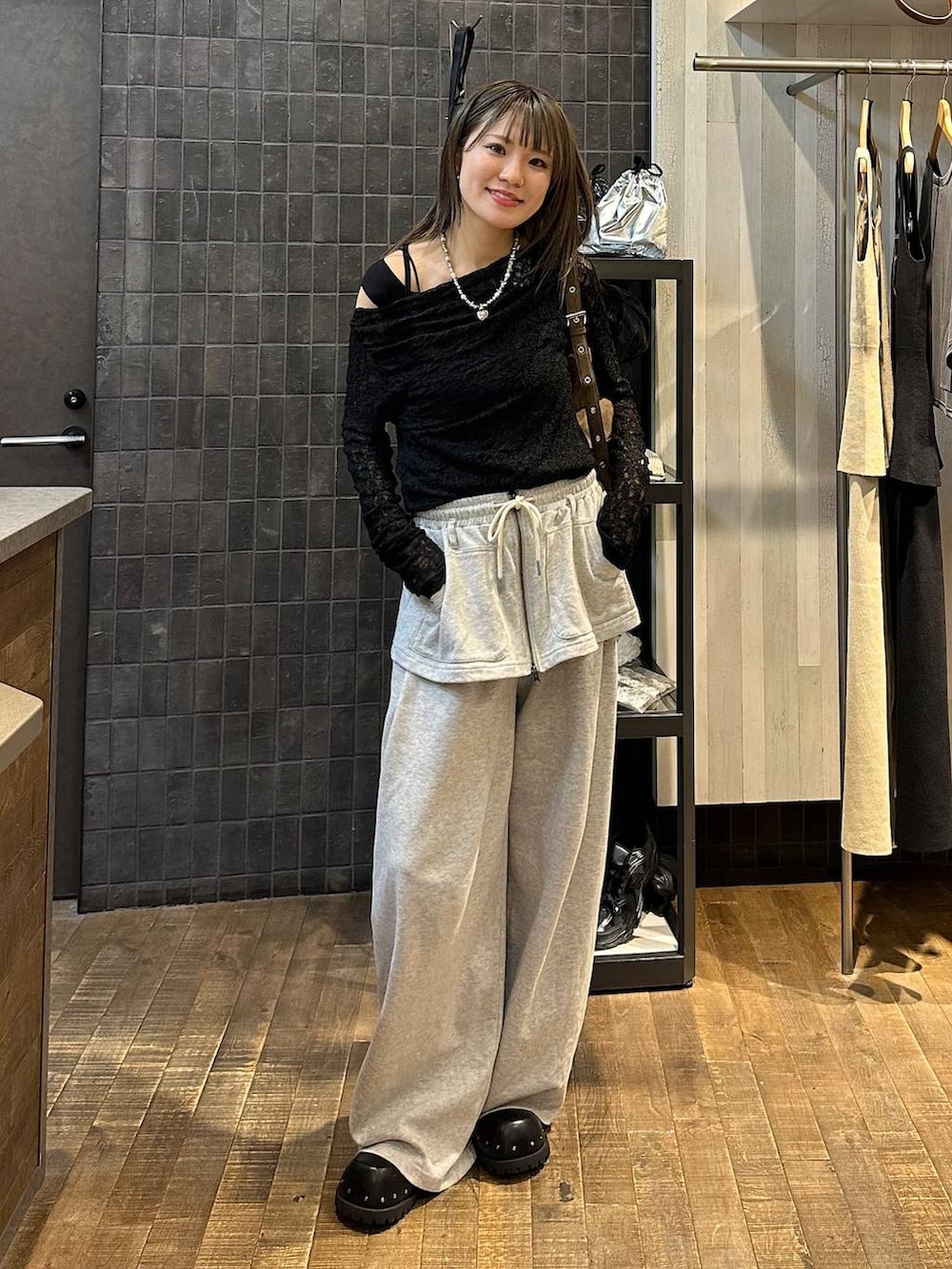 ブラウン系のショルダーバッグ、グレー系のスウェットパンツ、ブラック系のサンダルを着用したレディースの夏コーディネートの4枚目の写真