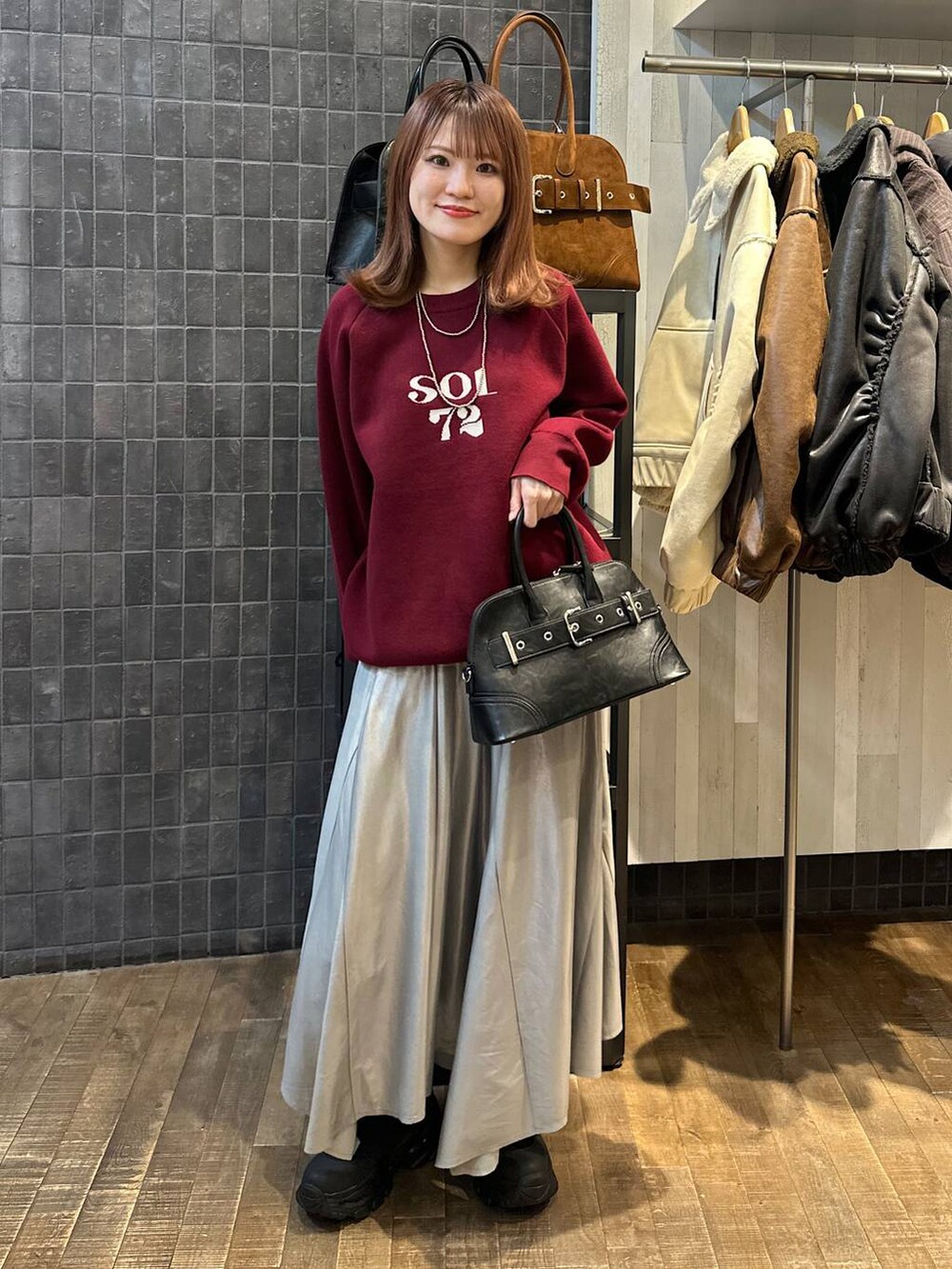 ブラック系のブーツ、ブラック系のボストンバッグ、シルバー系のスカートを着用したレディースの秋コーディネートの4枚目の写真