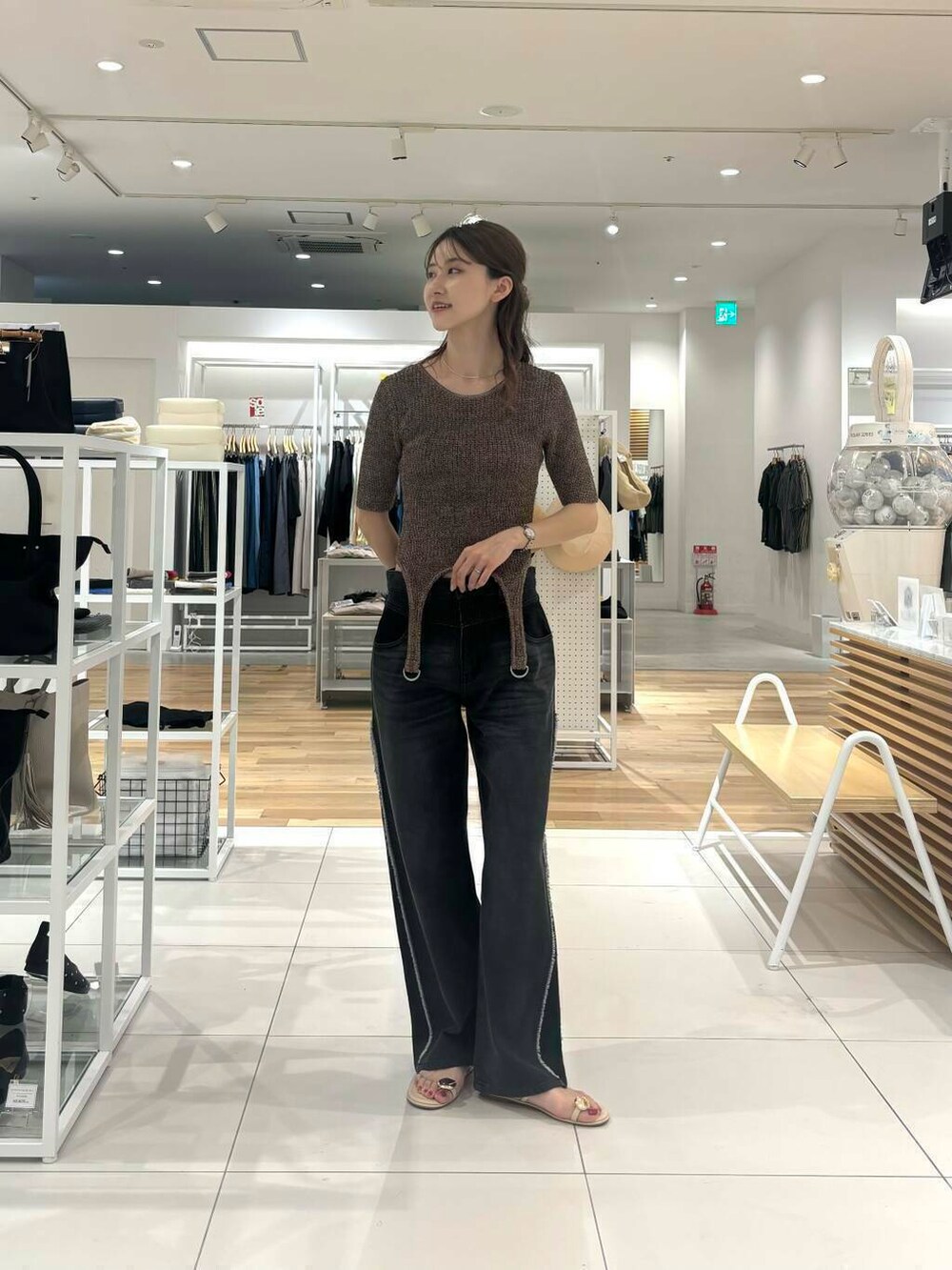 ブラック系のデニムパンツ、ブラウン系のニット/セーターを着用したレディースの夏コーディネートの2枚目の写真