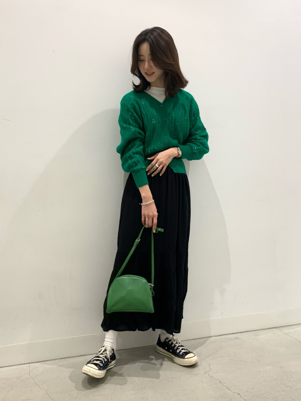 グリーン系のカーディガン/ボレロ、ブラック系のスカート、グリーン系のショルダーバッグを着用したレディースの冬コーディネートの2枚目の写真