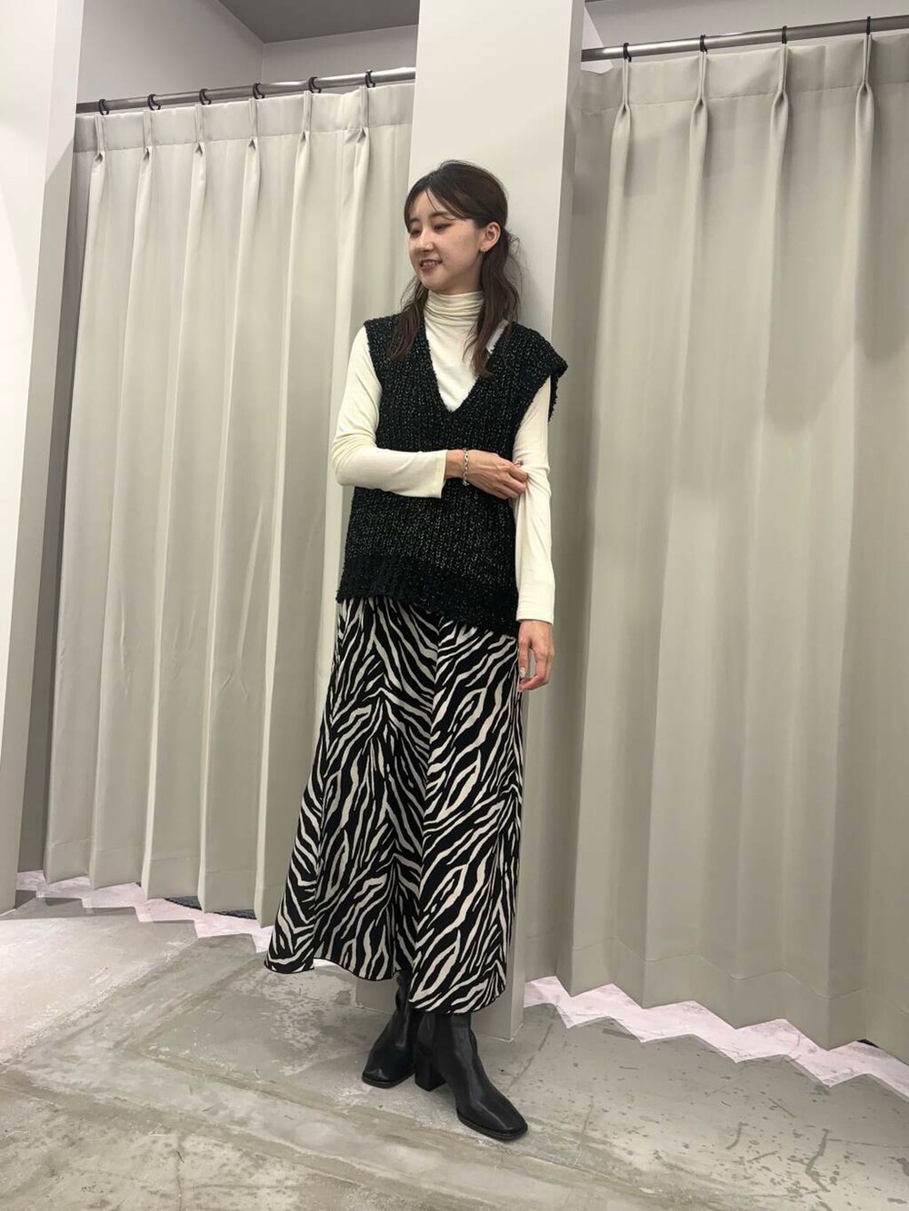 ブラック系のベスト、ブラック系のブーツ、ホワイト系のTシャツ/カットソーを着用したレディースの秋コーディネートの2枚目の写真