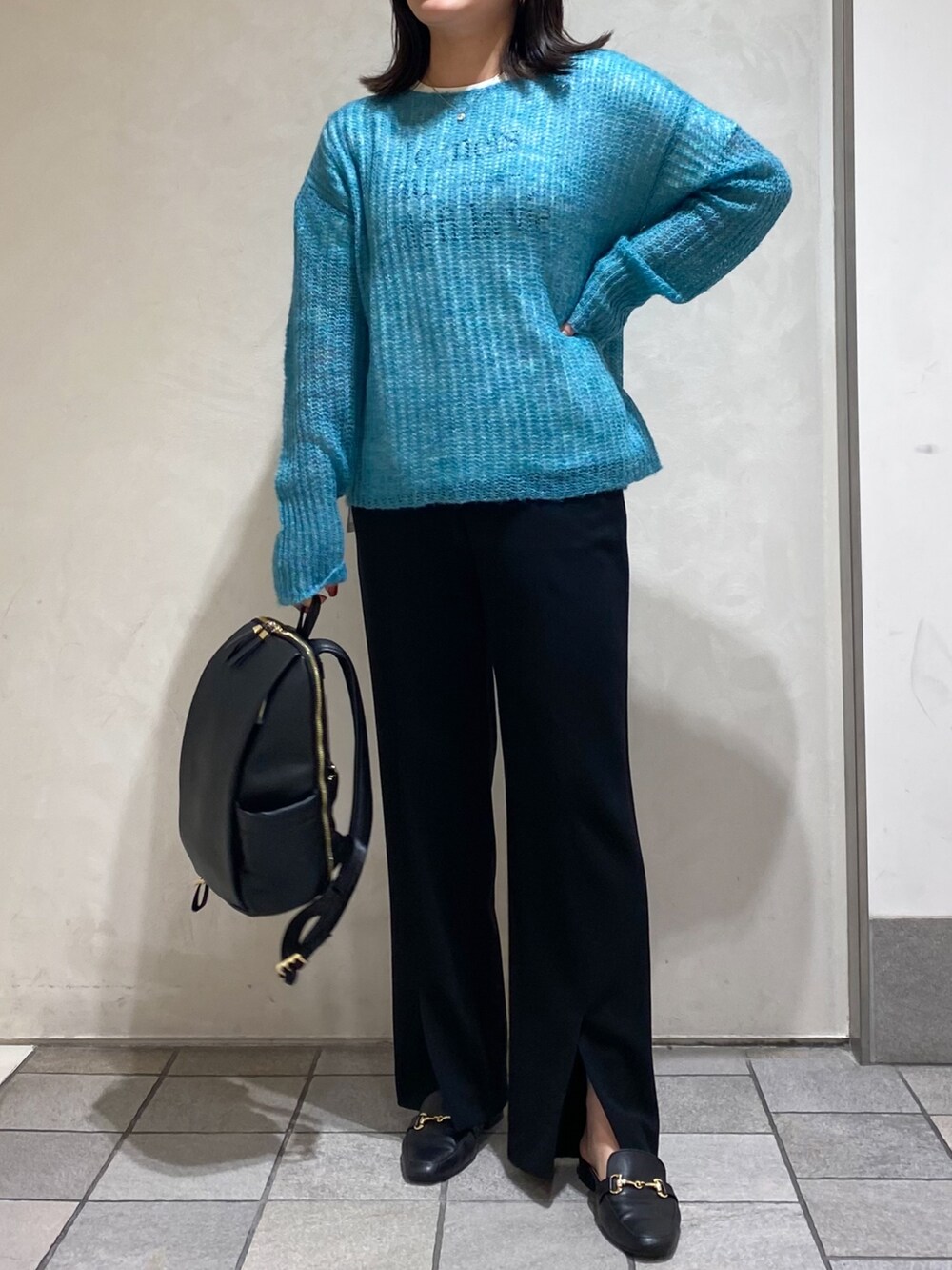 グリーン系のニット/セーター、ブラック系のスラックス、ブラック系のバックパック/リュックを着用したレディースの秋コーディネートの4枚目の写真