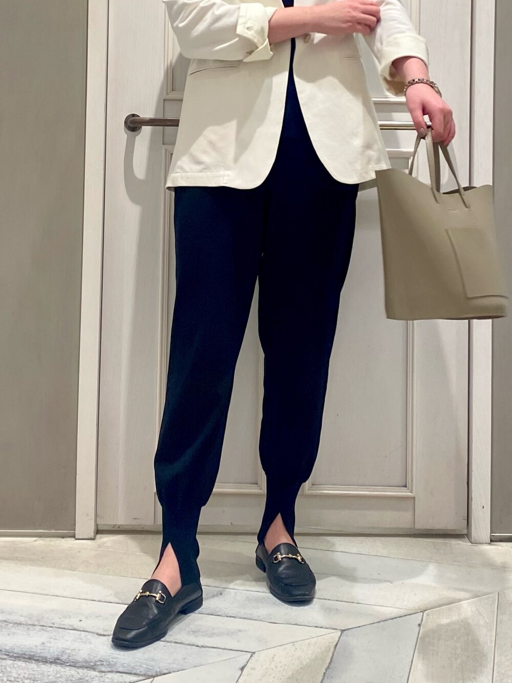 ホワイト系のノーカラージャケット、ブラック系のその他パンツ、ベージュ系のハンドバッグを着用したレディースの春コーディネートの2枚目の写真