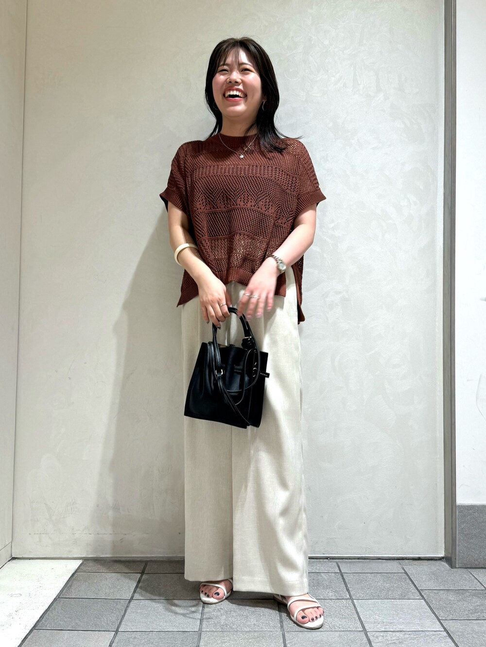ブラウン系のニット/セーター、ホワイト系のトートバッグを着用したレディースの夏コーディネートの2枚目の写真