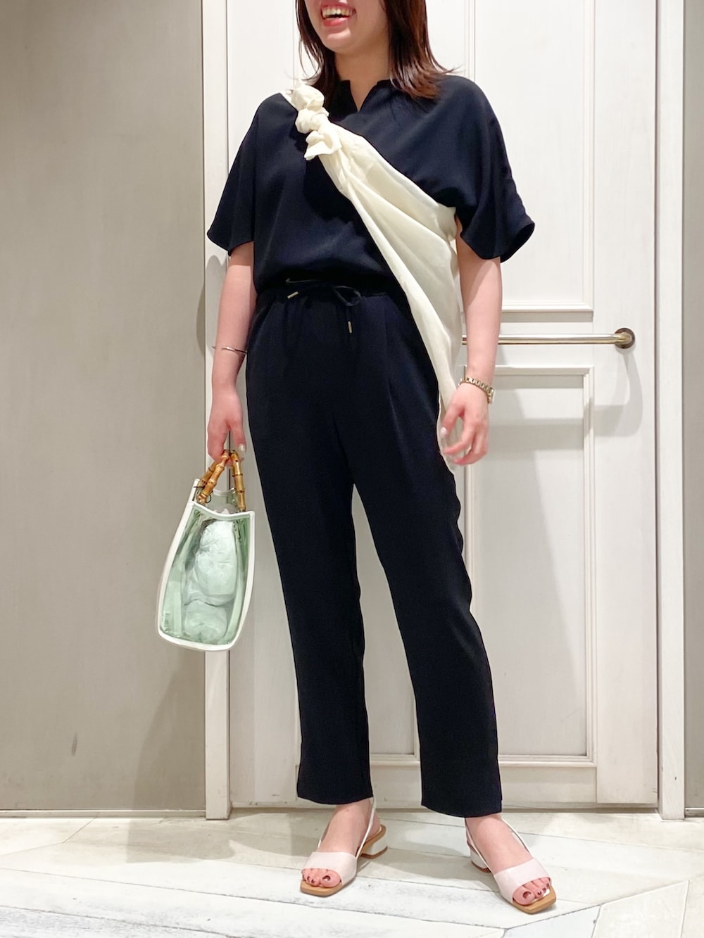 ブラック系のTシャツ/カットソー、ブラック系のスラックス、ホワイト系のトートバッグを着用したレディースの夏コーディネートの4枚目の写真