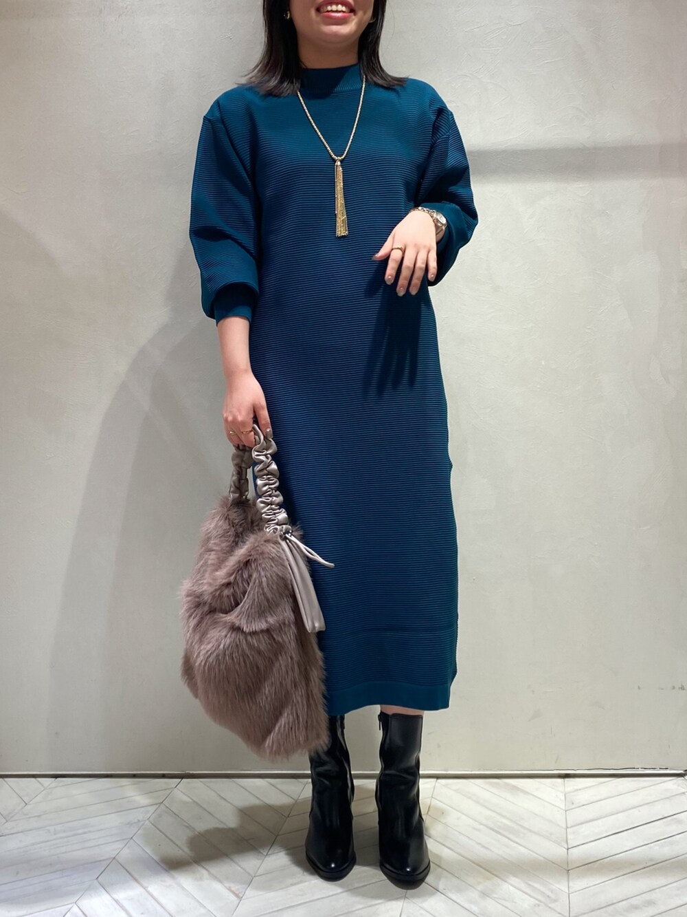 グリーン系のワンピース、ブラック系のブーツ、ブラウン系のトートバッグを着用したレディースの秋コーディネートの2枚目の写真