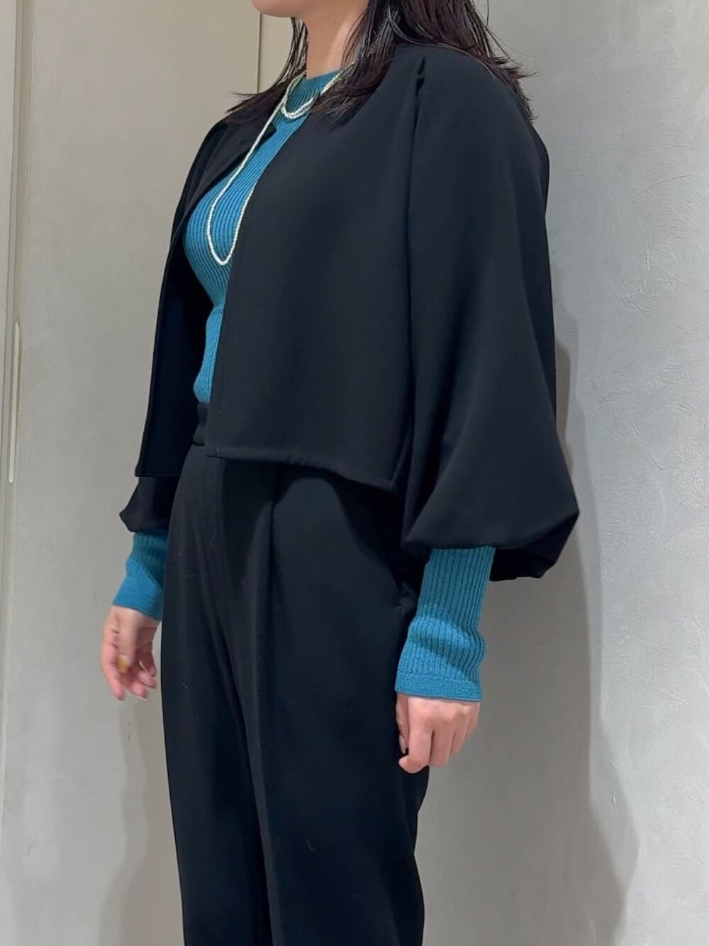 ブラック系のテーラードジャケット、ブルー系のニット/セーター、ブラック系のスラックスを着用したレディースの秋コーディネートの6枚目の写真