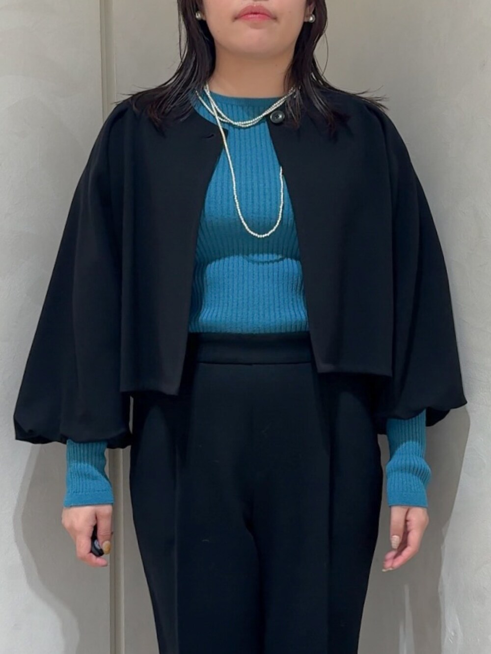 ブラック系のテーラードジャケット、ブルー系のニット/セーター、ブラック系のスラックスを着用したレディースの秋コーディネートの7枚目の写真