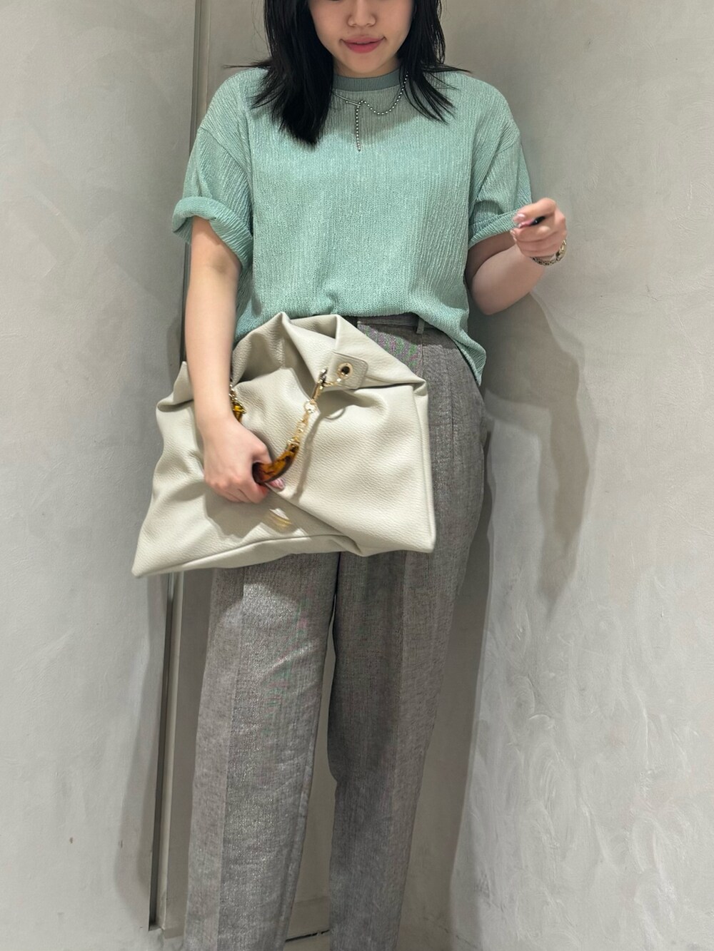 グリーン系のTシャツ/カットソー、グレー系のスラックス、ホワイト系のトートバッグを着用したレディースの夏コーディネートの3枚目の写真