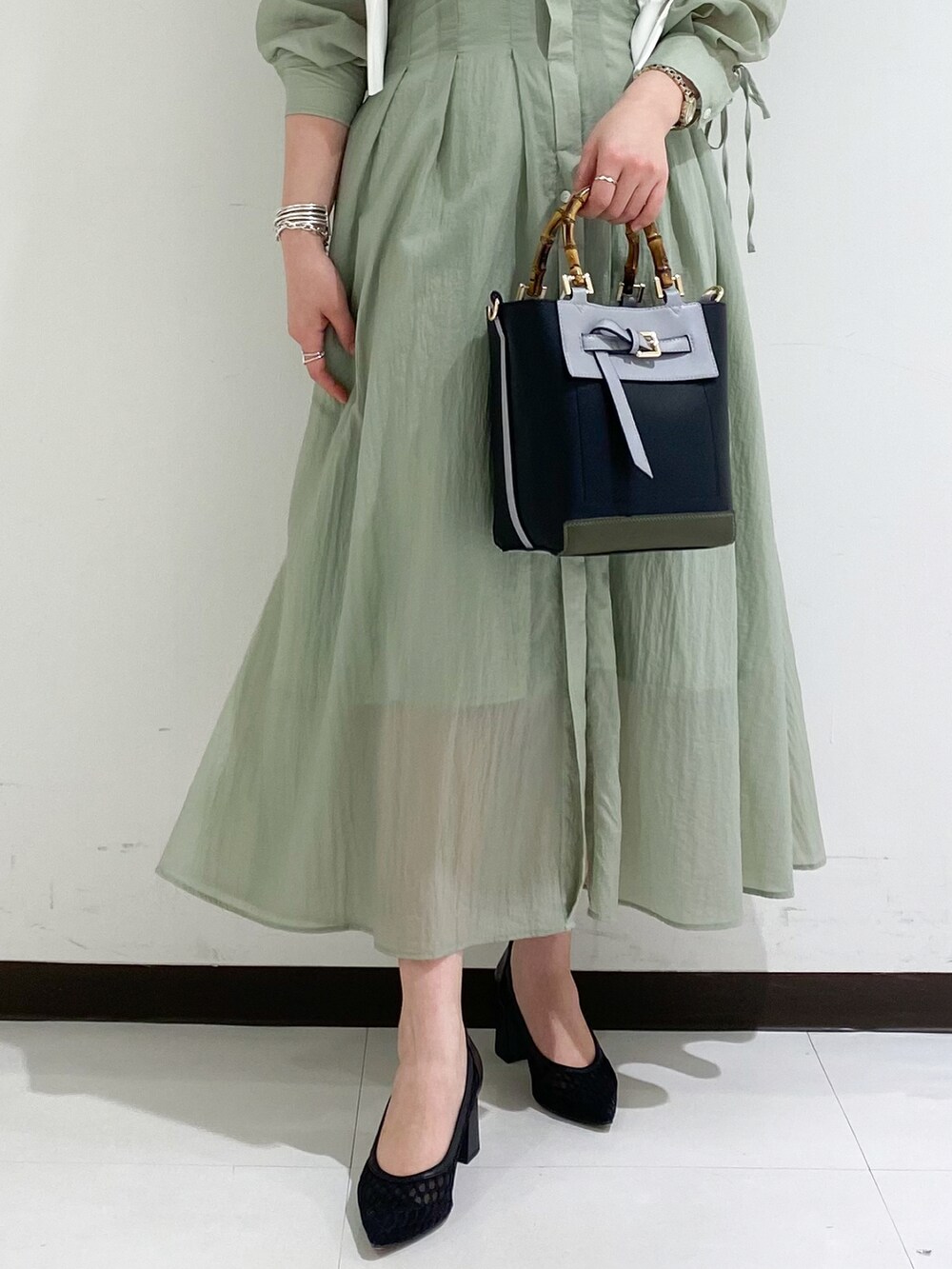 ホワイト系のカーディガン/ボレロ、グリーン系のワンピース、ブラック系のトートバッグを着用したレディースの春コーディネートの3枚目の写真