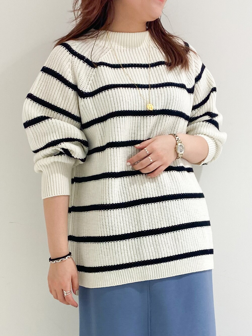 ホワイト系のニット/セーター、ブルー系のスカート、ブラック系のブーツを着用したレディースの冬コーディネートの4枚目の写真