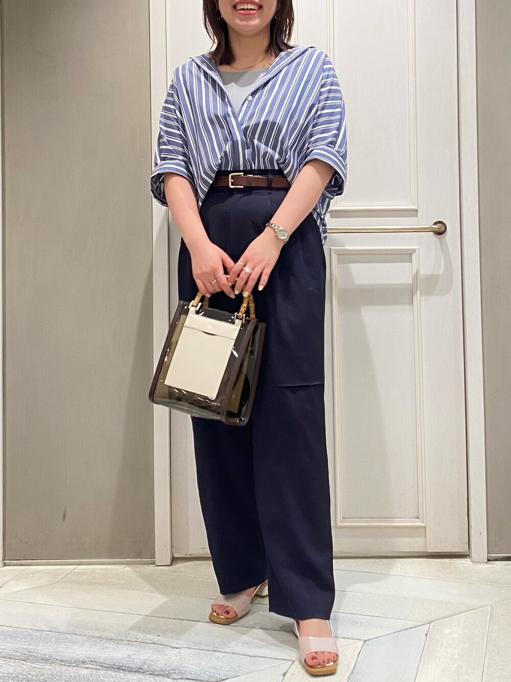 ブラウン系のトートバッグ、ホワイト系のサンダル、ブルー系のその他パンツを着用したレディースの夏コーディネートの2枚目の写真