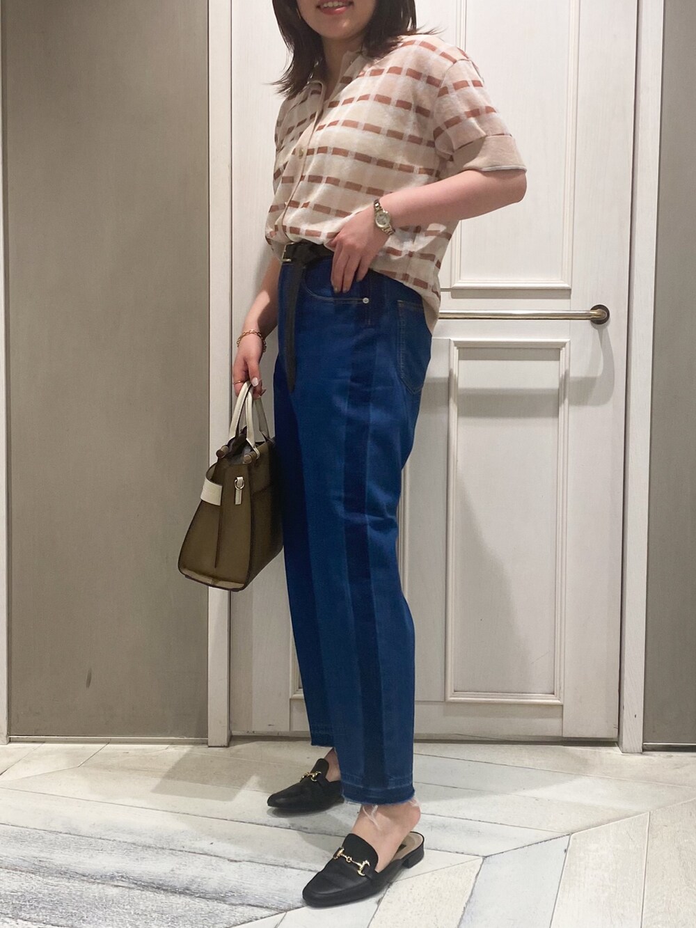 ベージュ系のニット/セーター、ベージュ系のショルダーバッグ、ブルー系のデニムパンツを着用したレディースの春コーディネートの2枚目の写真