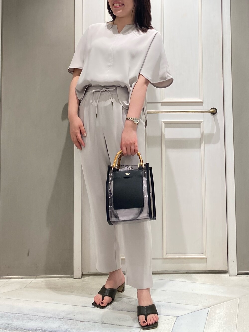 ブラック系のスラックス、ブラック系のトートバッグ、グリーン系のサンダルを着用したレディースの春コーディネートの2枚目の写真