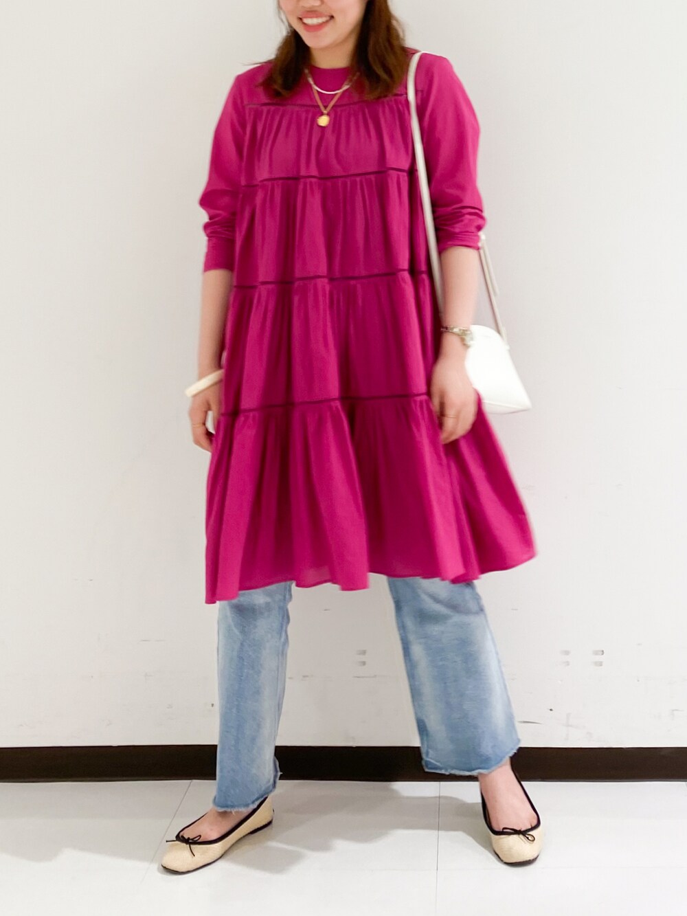 ピンク系のワンピース、ブルー系のデニムパンツ、ホワイト系のショルダーバッグを着用したレディースの春コーディネートの3枚目の写真