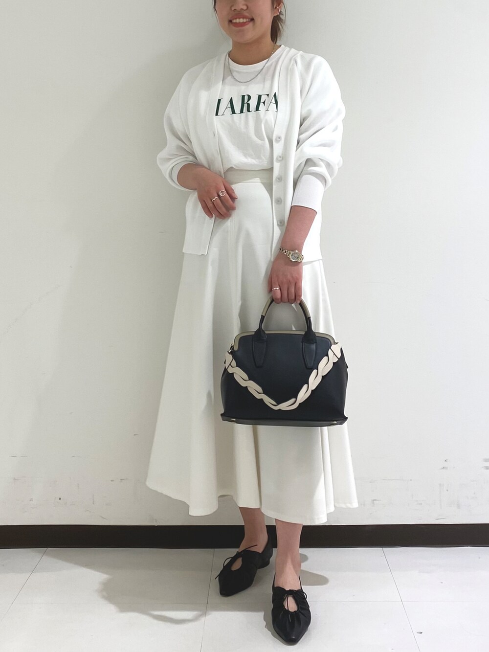 ホワイト系のカーディガン/ボレロ、ホワイト系のスカート、ブラック系のトートバッグを着用したレディースの春コーディネートの2枚目の写真