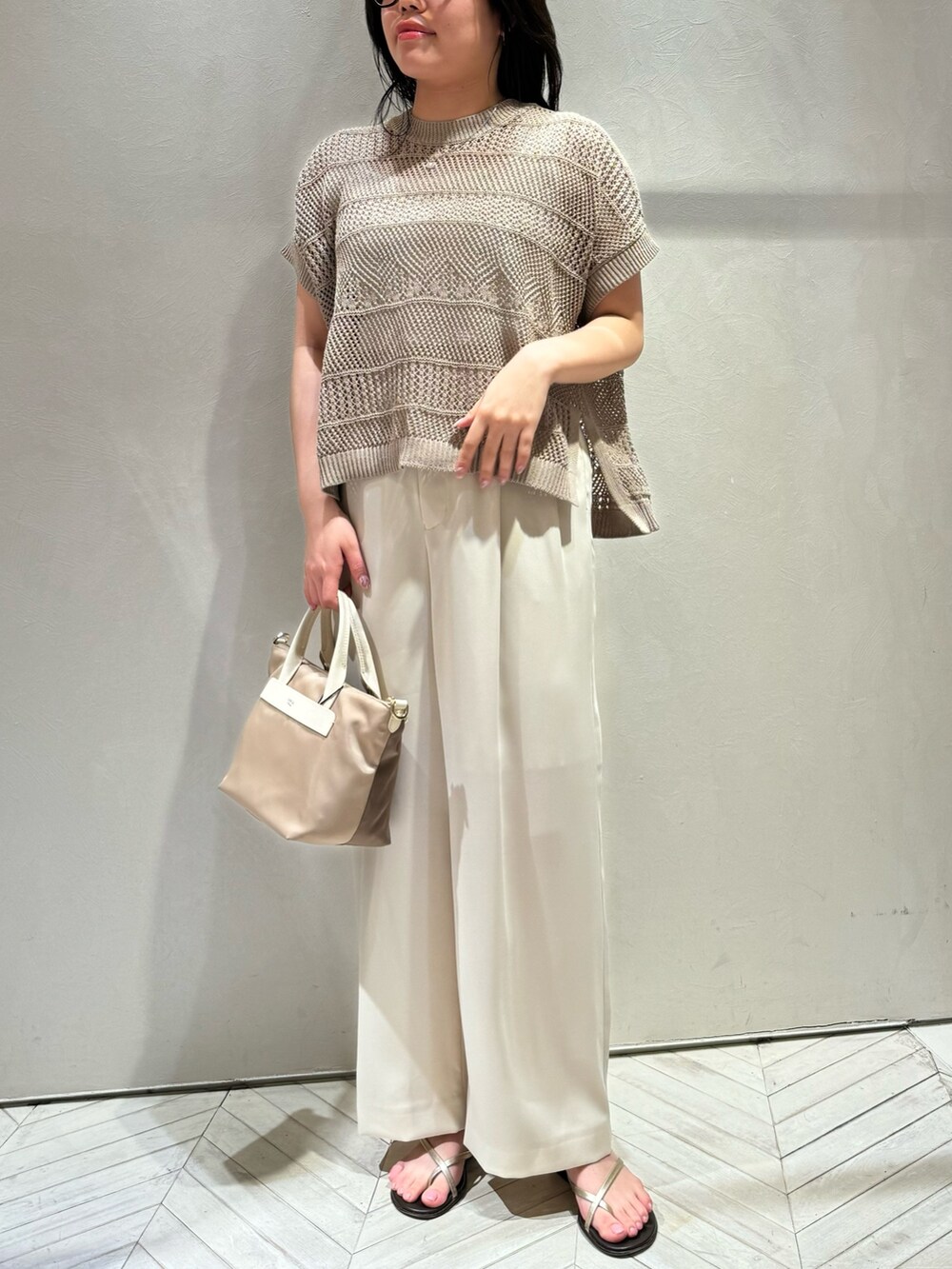 ベージュ系のニット/セーター、ホワイト系のスラックスを着用したレディースの春コーディネートの3枚目の写真