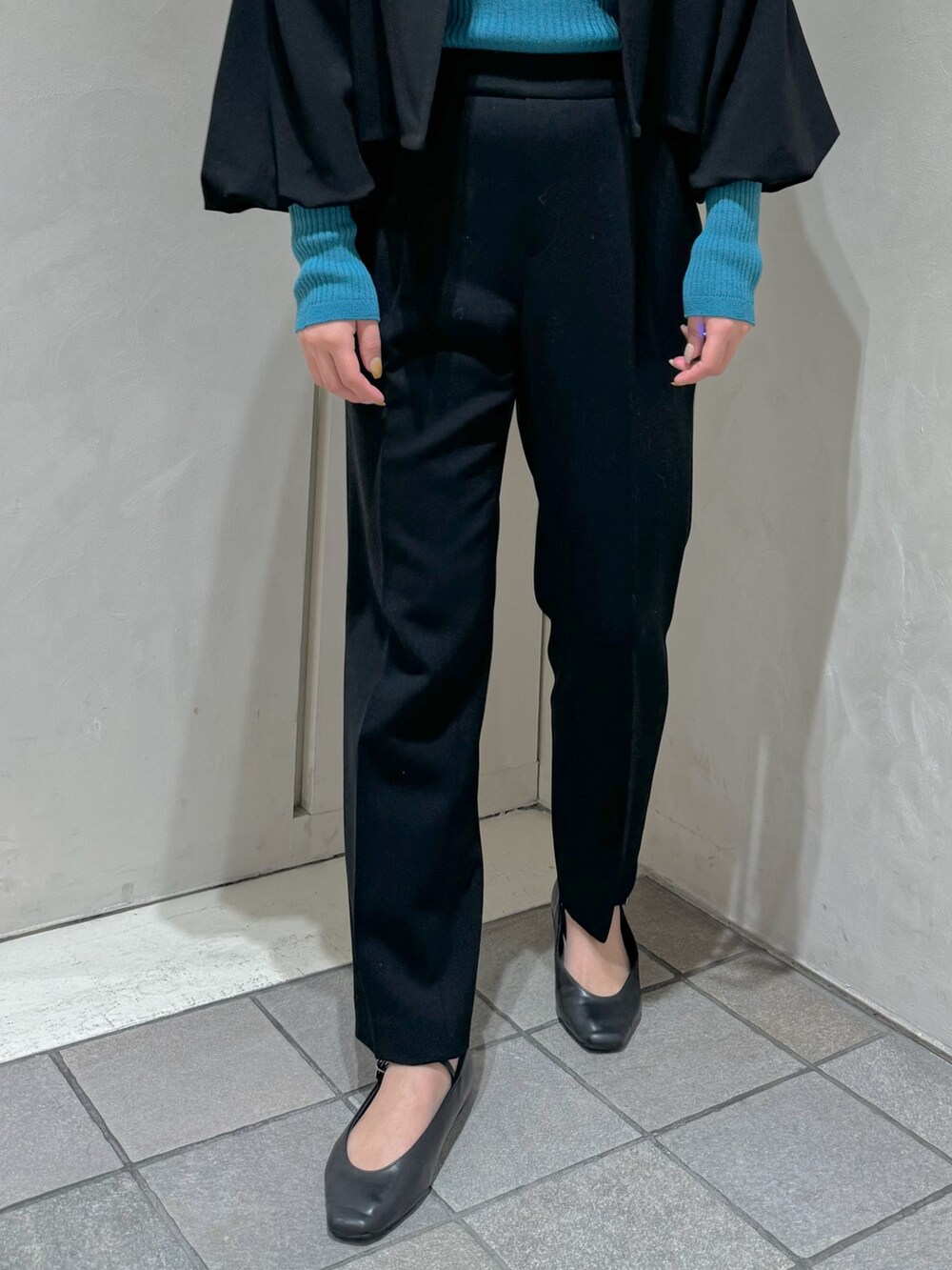 ブラック系のテーラードジャケット、ブルー系のニット/セーター、ブラック系のスラックスを着用したレディースの秋コーディネートの4枚目の写真