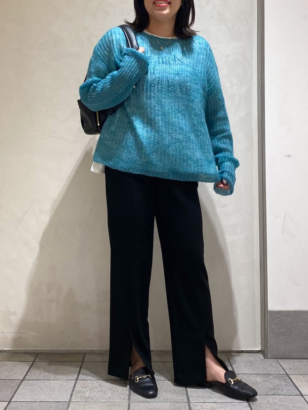 グリーン系のニット/セーター、ブラック系のスラックス、ブラック系のバックパック/リュックを着用したレディースの秋コーディネートの2枚目の写真