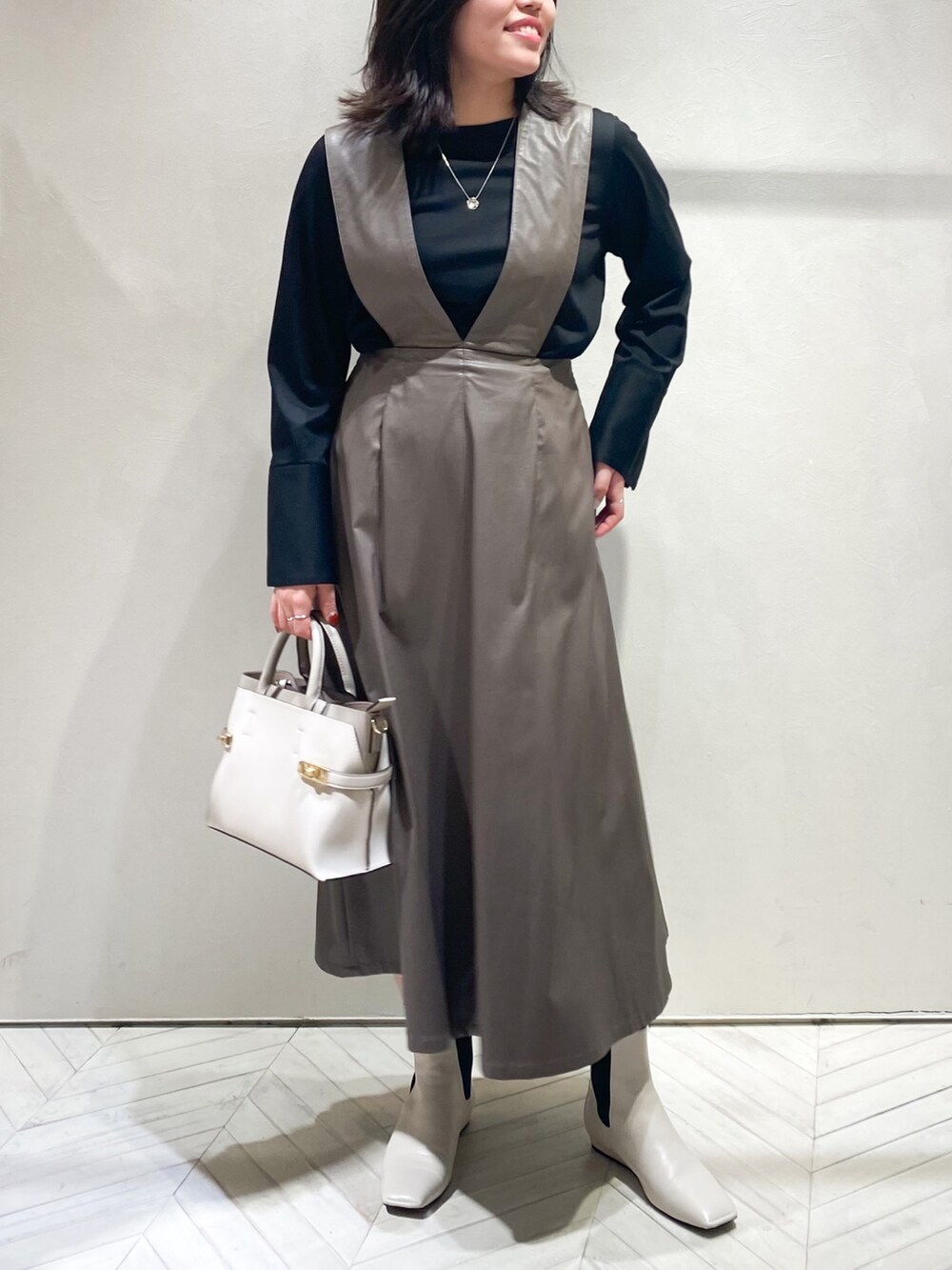 ブラウン系のジャンパースカート、ブラック系のTシャツ/カットソー、ホワイト系のショルダーバッグを着用したレディースの秋コーディネートの3枚目の写真
