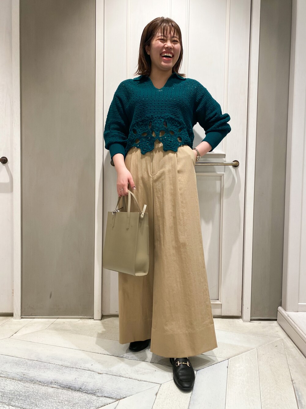 ベージュ系のトートバッグ、ベージュ系のその他パンツ、グリーン系のニット/セーターを着用したレディースの冬コーディネートの3枚目の写真