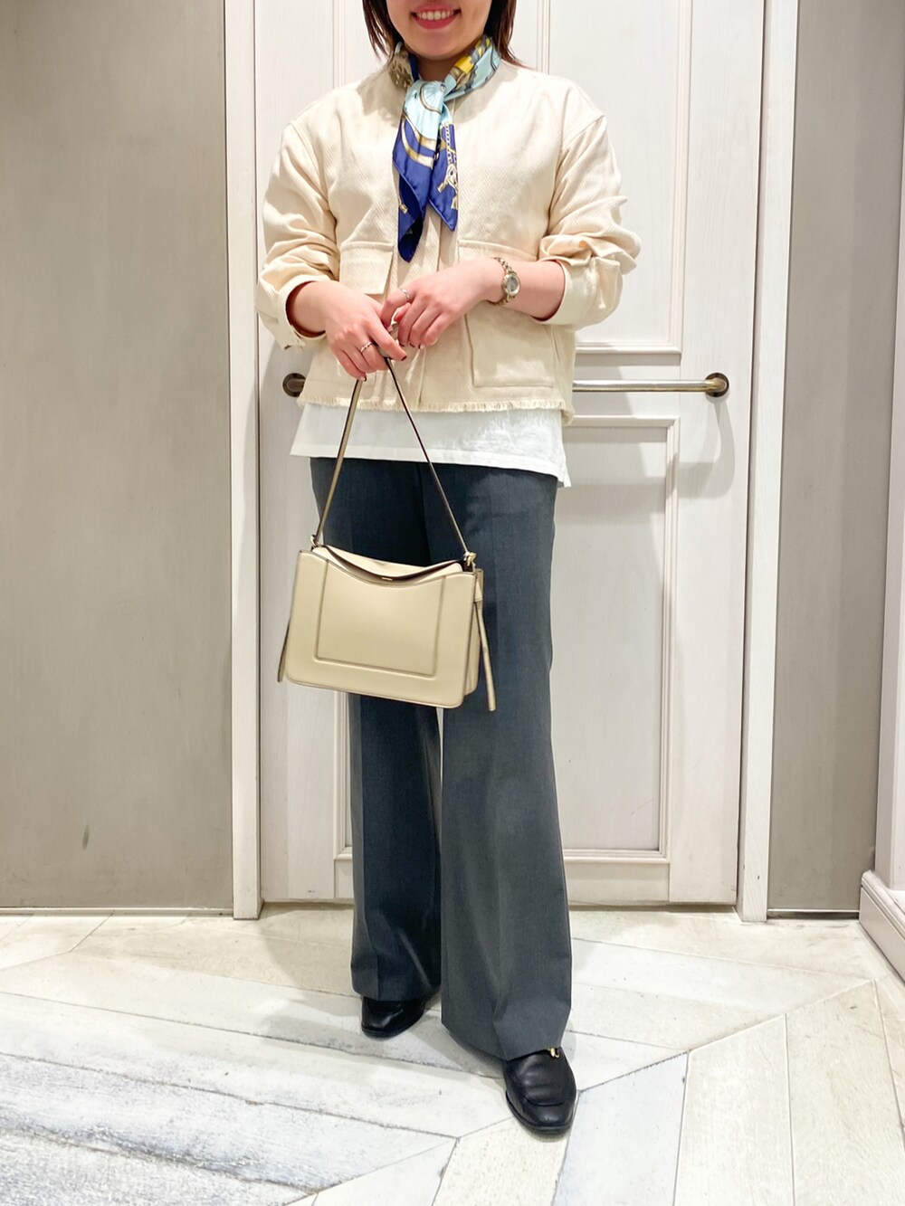 ホワイト系のブルゾン、ホワイト系のショルダーバッグ、グレー系のスラックスを着用したレディースの冬コーディネートの4枚目の写真