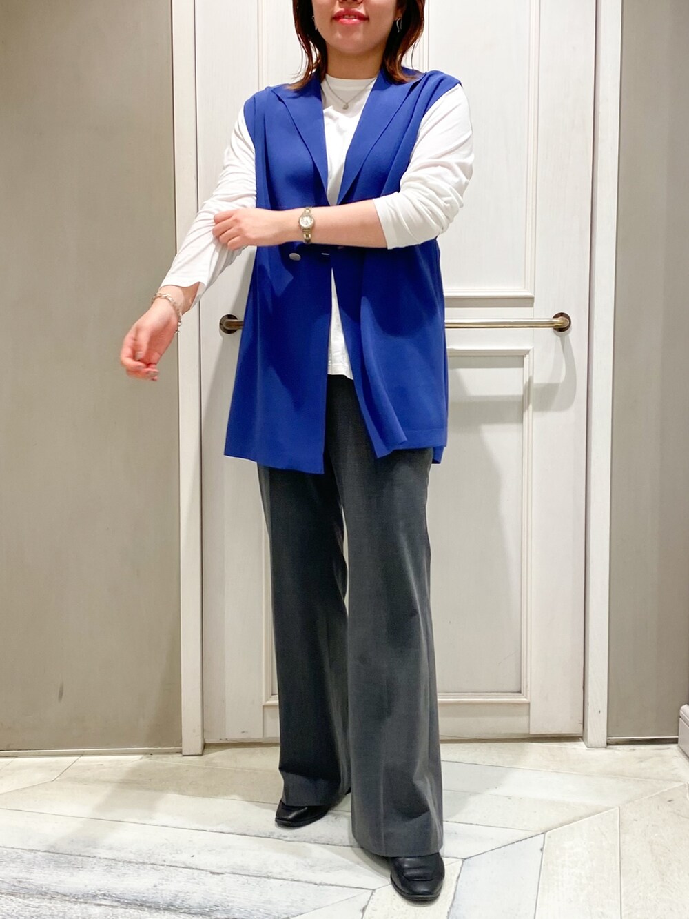 ブルー系のニット/セーター、ホワイト系のTシャツ/カットソー、グレー系のスラックスを着用したレディースの春コーディネートの3枚目の写真