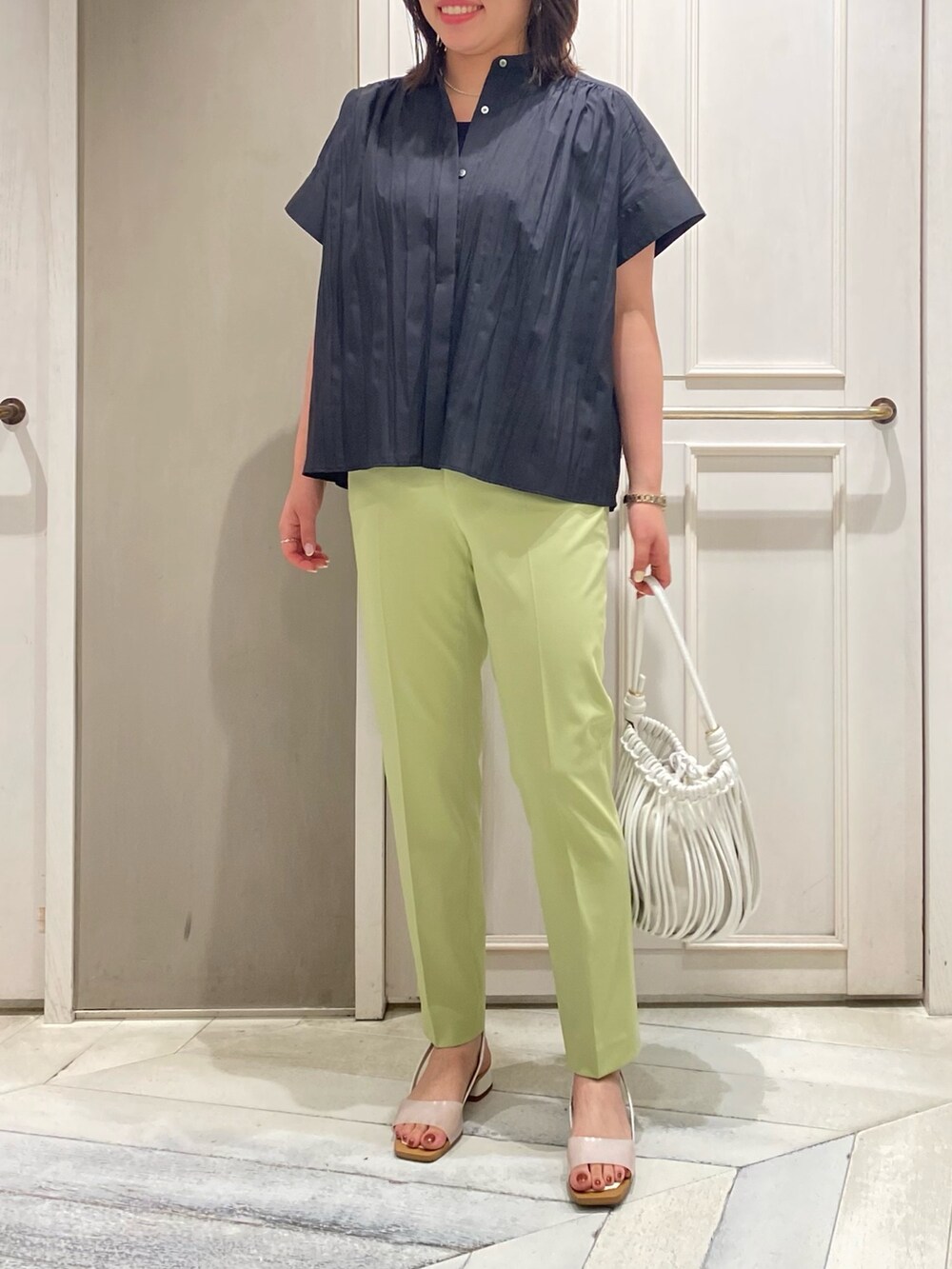 ブラック系のシャツ/ブラウス、グリーン系のスラックス、ホワイト系のサンダルを着用したレディースの夏コーディネートの3枚目の写真