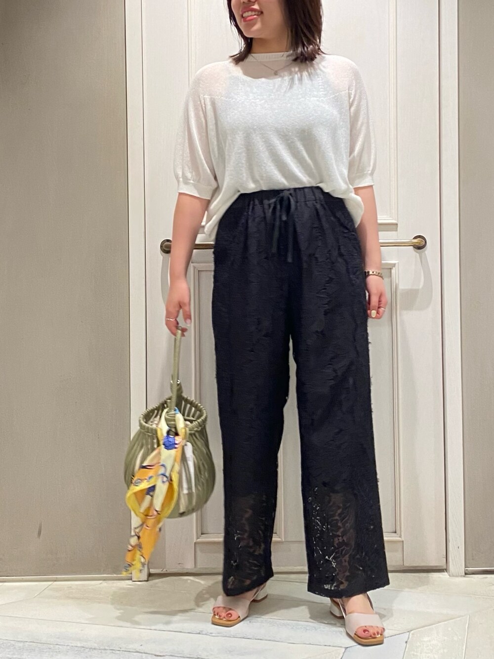 ホワイト系のニット/セーター、ブラック系のその他パンツ、グリーン系のショルダーバッグを着用したレディースの夏コーディネートの5枚目の写真