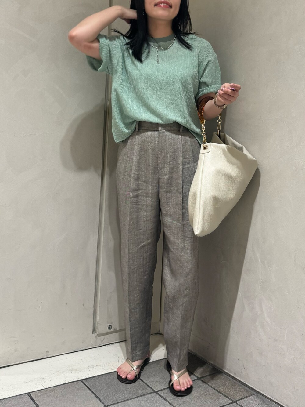 グリーン系のTシャツ/カットソー、グレー系のスラックス、ホワイト系のトートバッグを着用したレディースの夏コーディネートの4枚目の写真