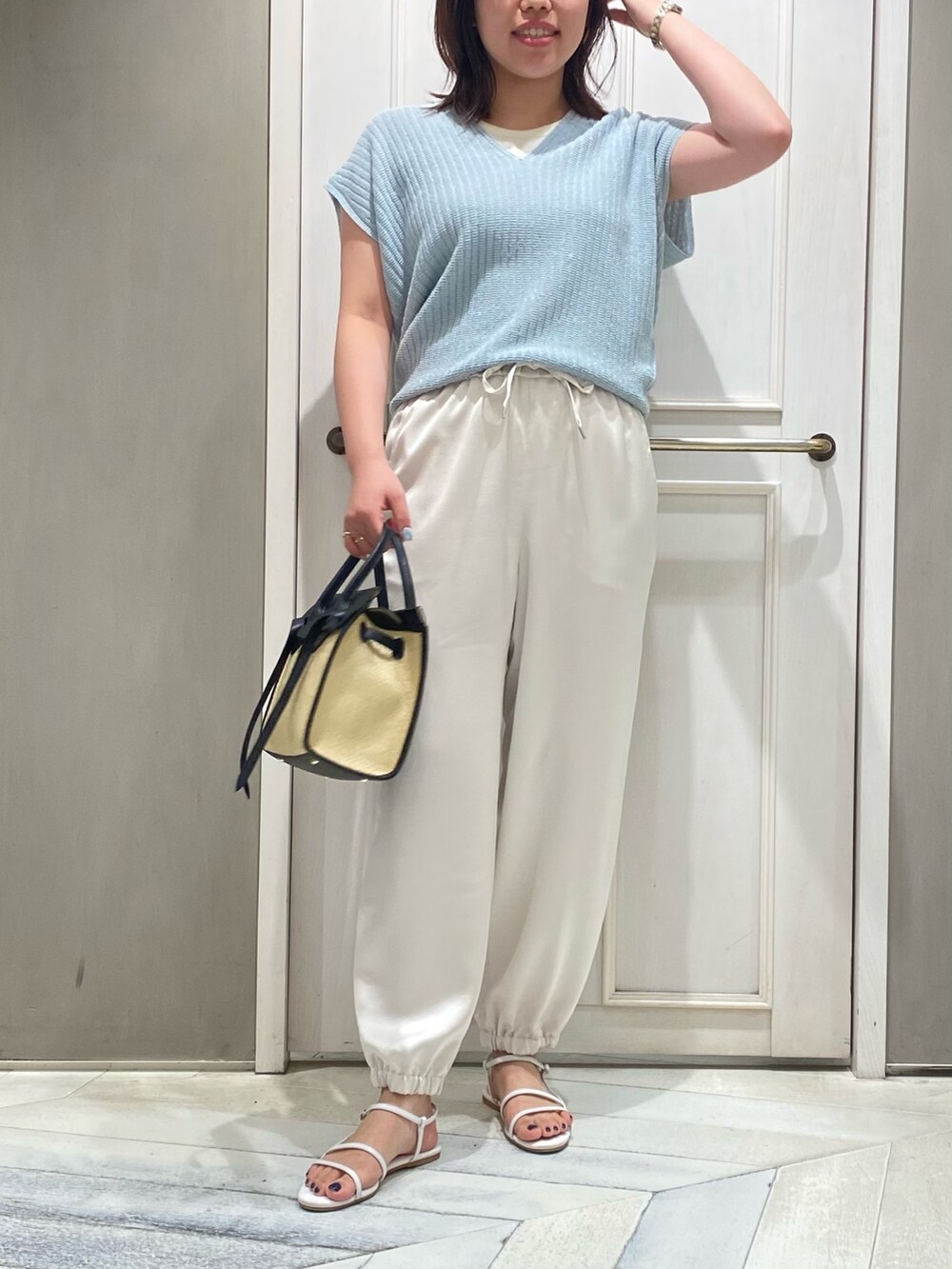 ブルー系のニット/セーター、ホワイト系のその他パンツ、ホワイト系のサンダルを着用したレディースの夏コーディネートの4枚目の写真